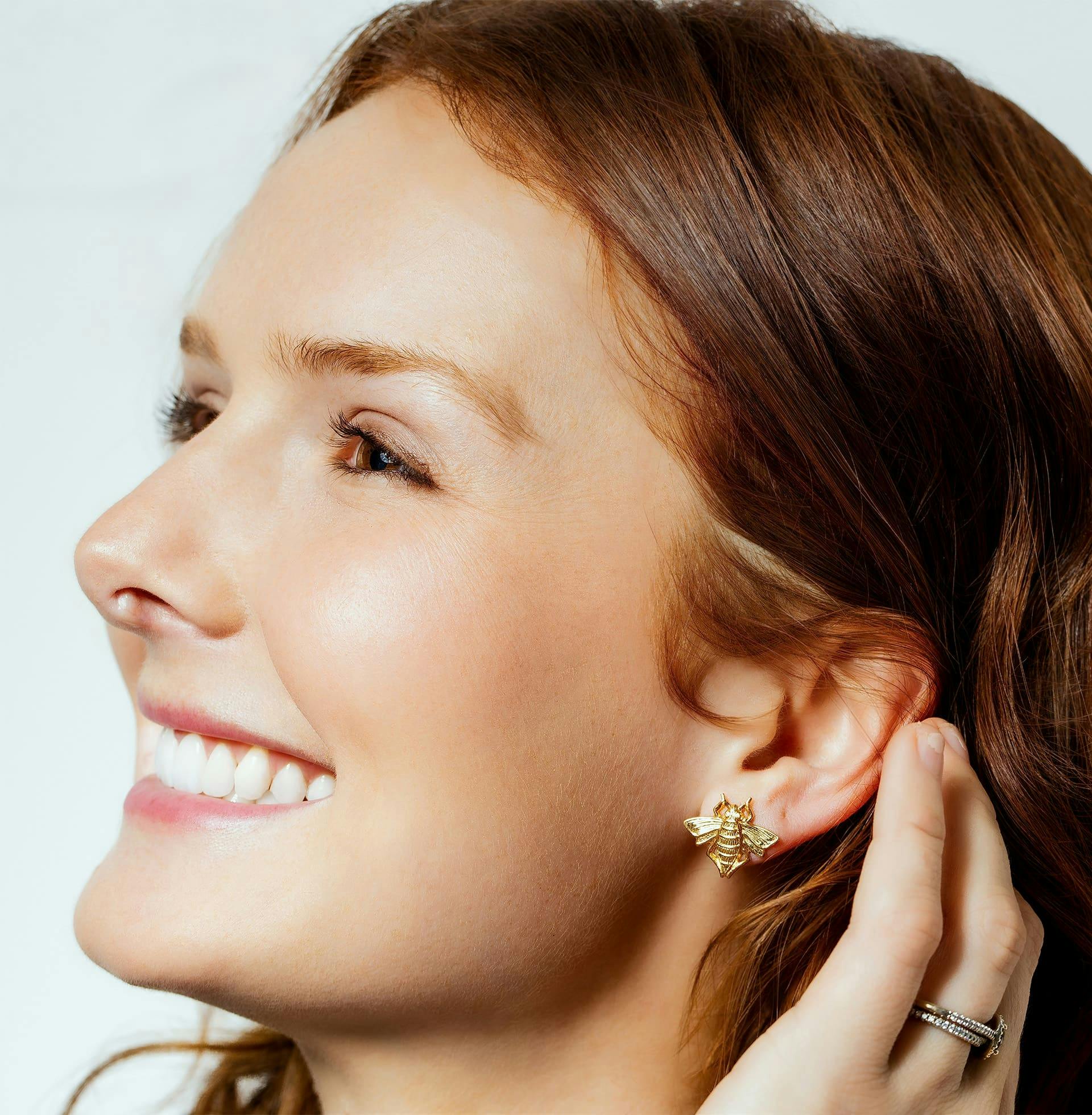 woman smiling while putting her hair behind her ear
