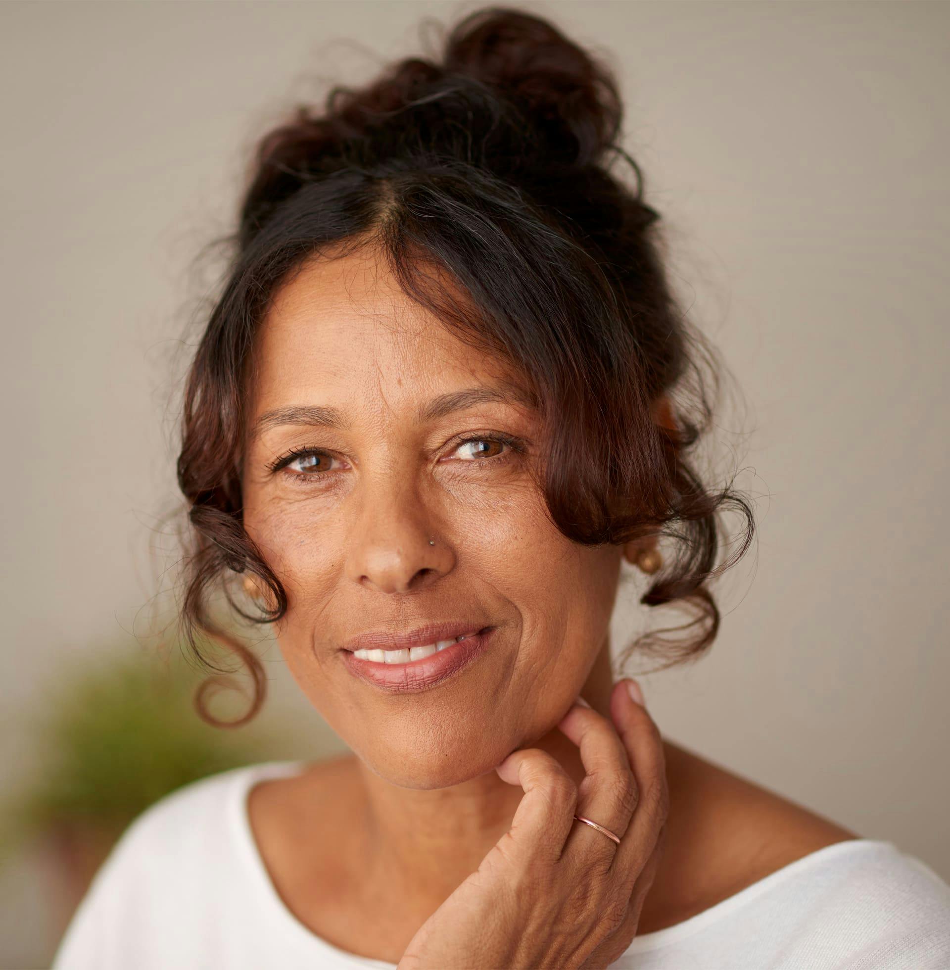 woman with her hair in a bun grinning forward