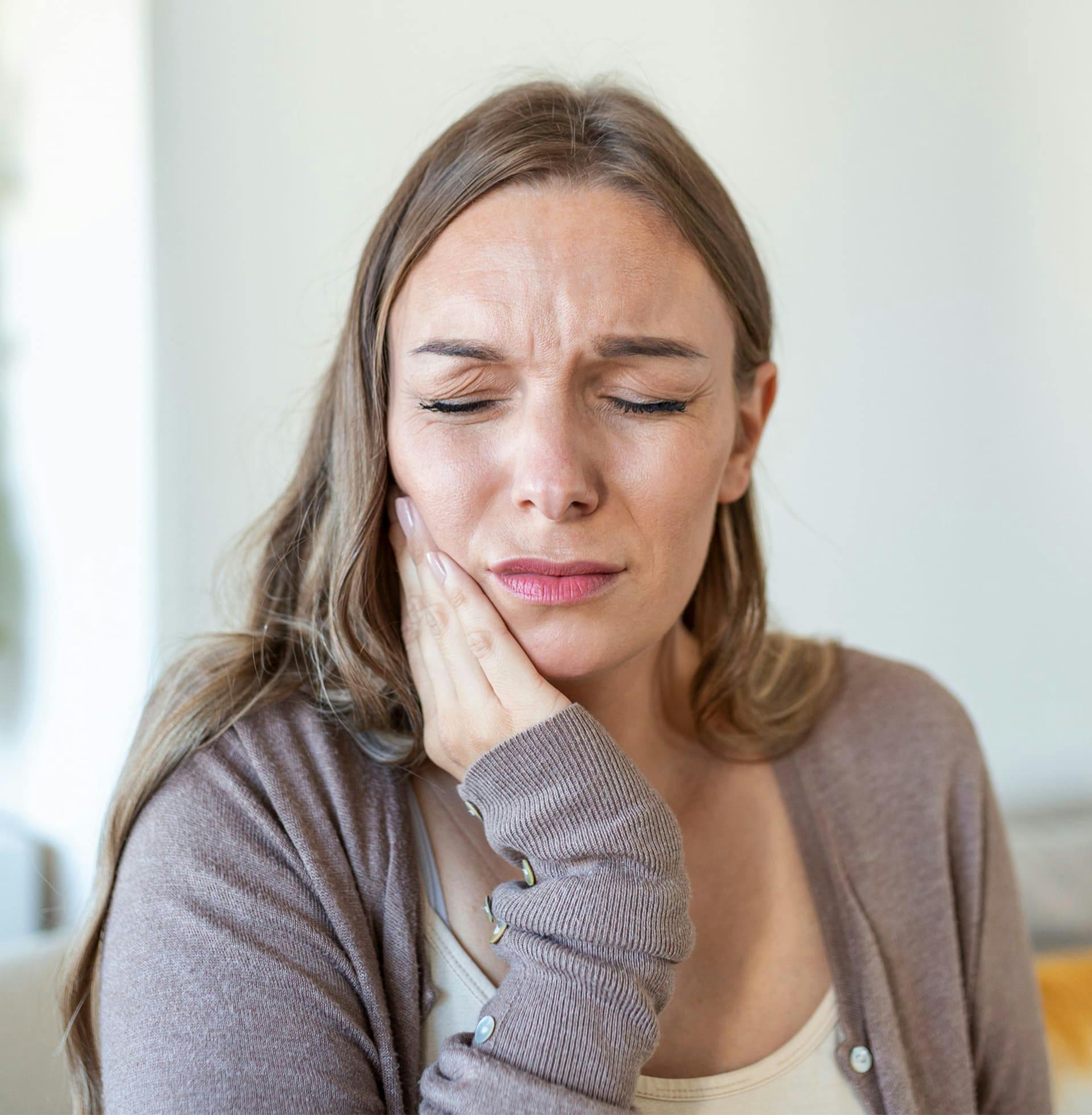 woman holding her cheek while in pain