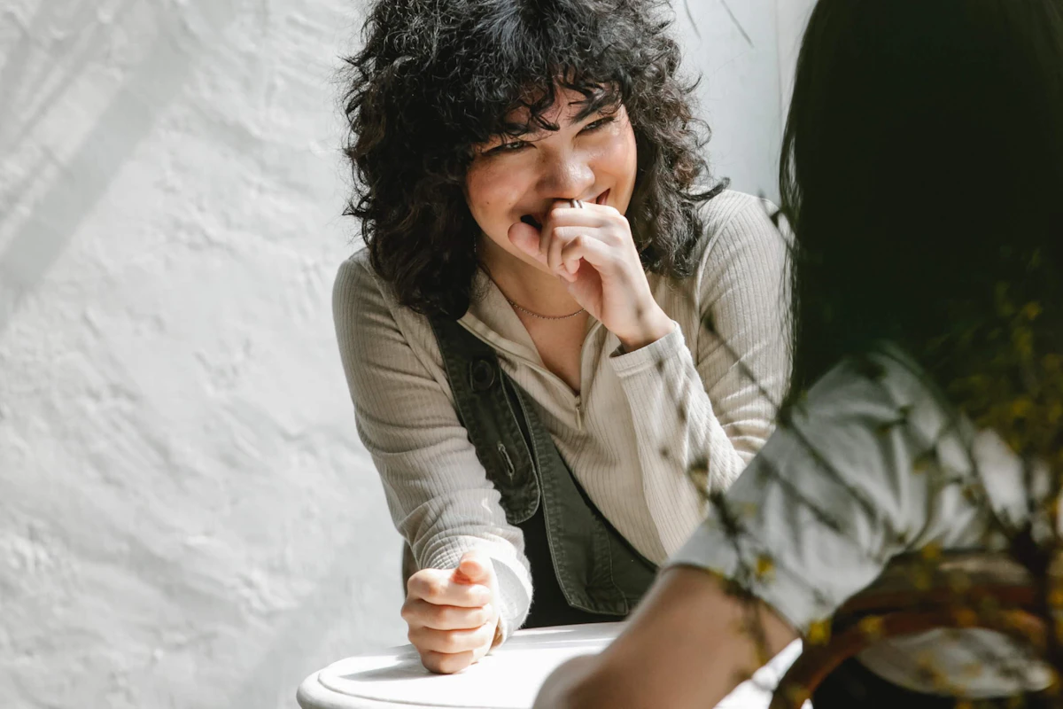 Eine Frau die in einem Kaffee lächelnd zu einer anderen schaut, sie diskutieren das Thema Blockchain.