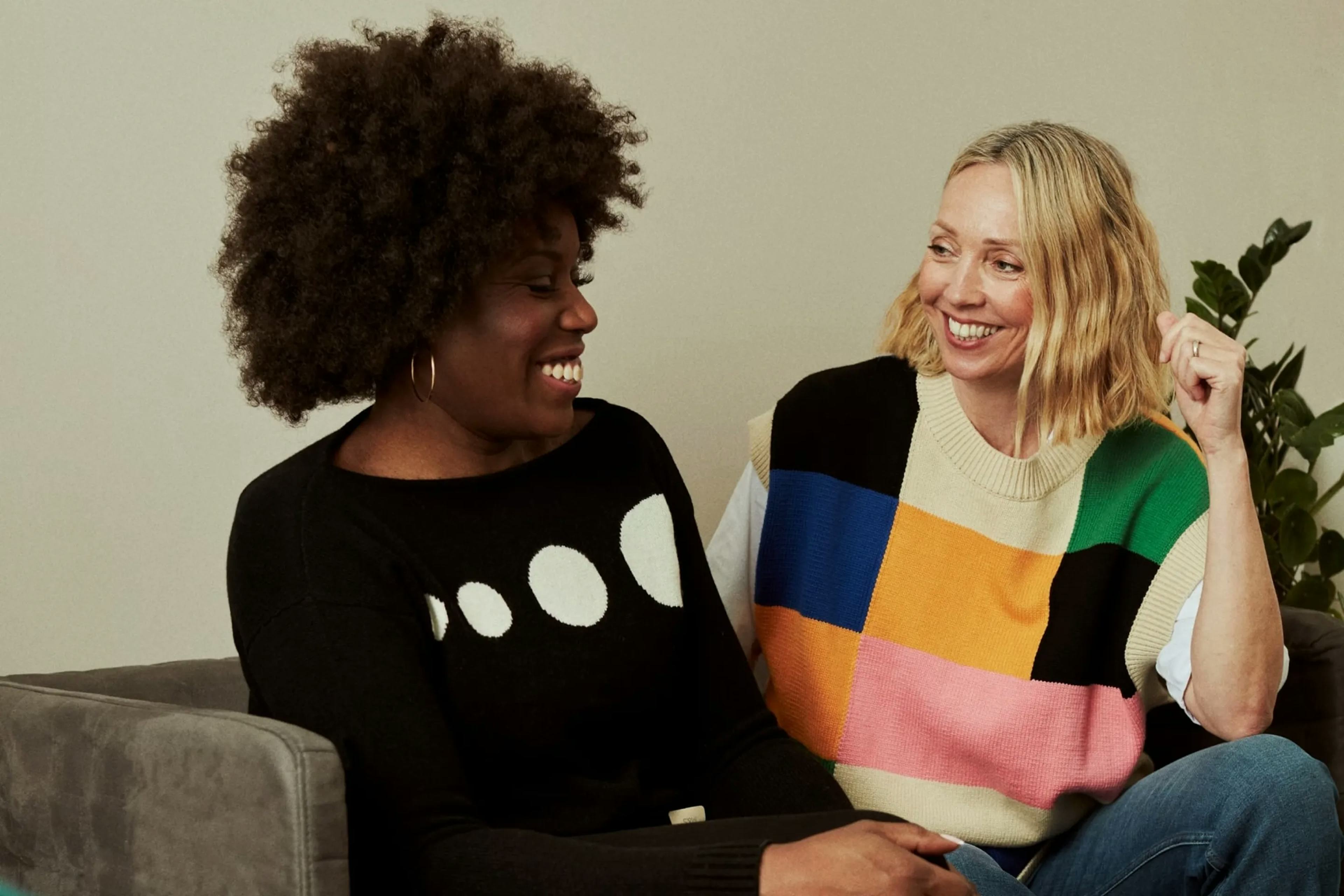 Een kleurrijke foto van twee vrouwen, pratend op een zitbank, blij.