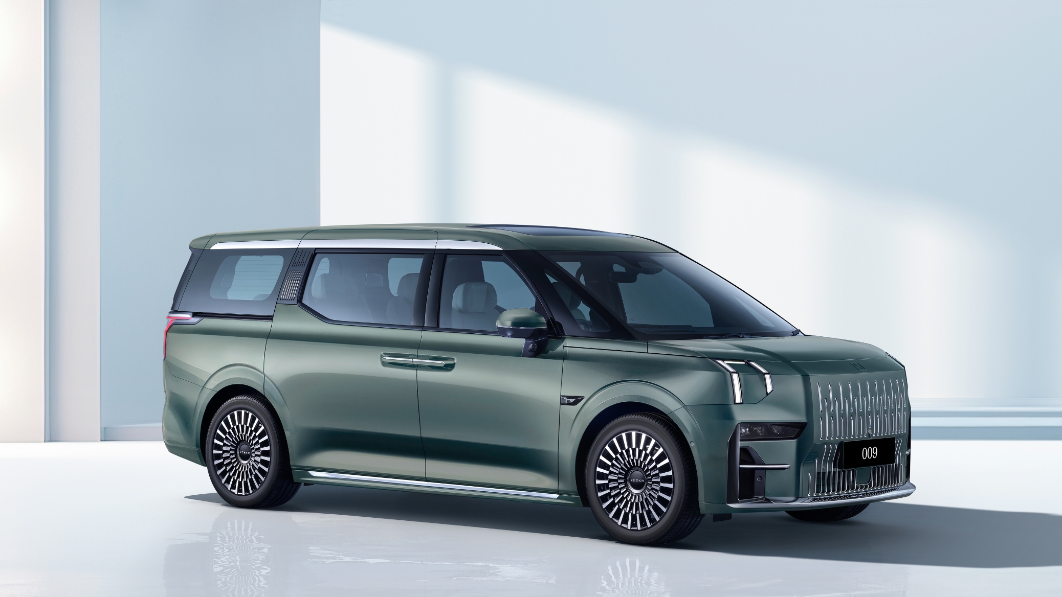 Side-front view of the Zeekr 009 electric MPV in Mineral Green, showcasing its bold design, signature grille, and aero wheels.