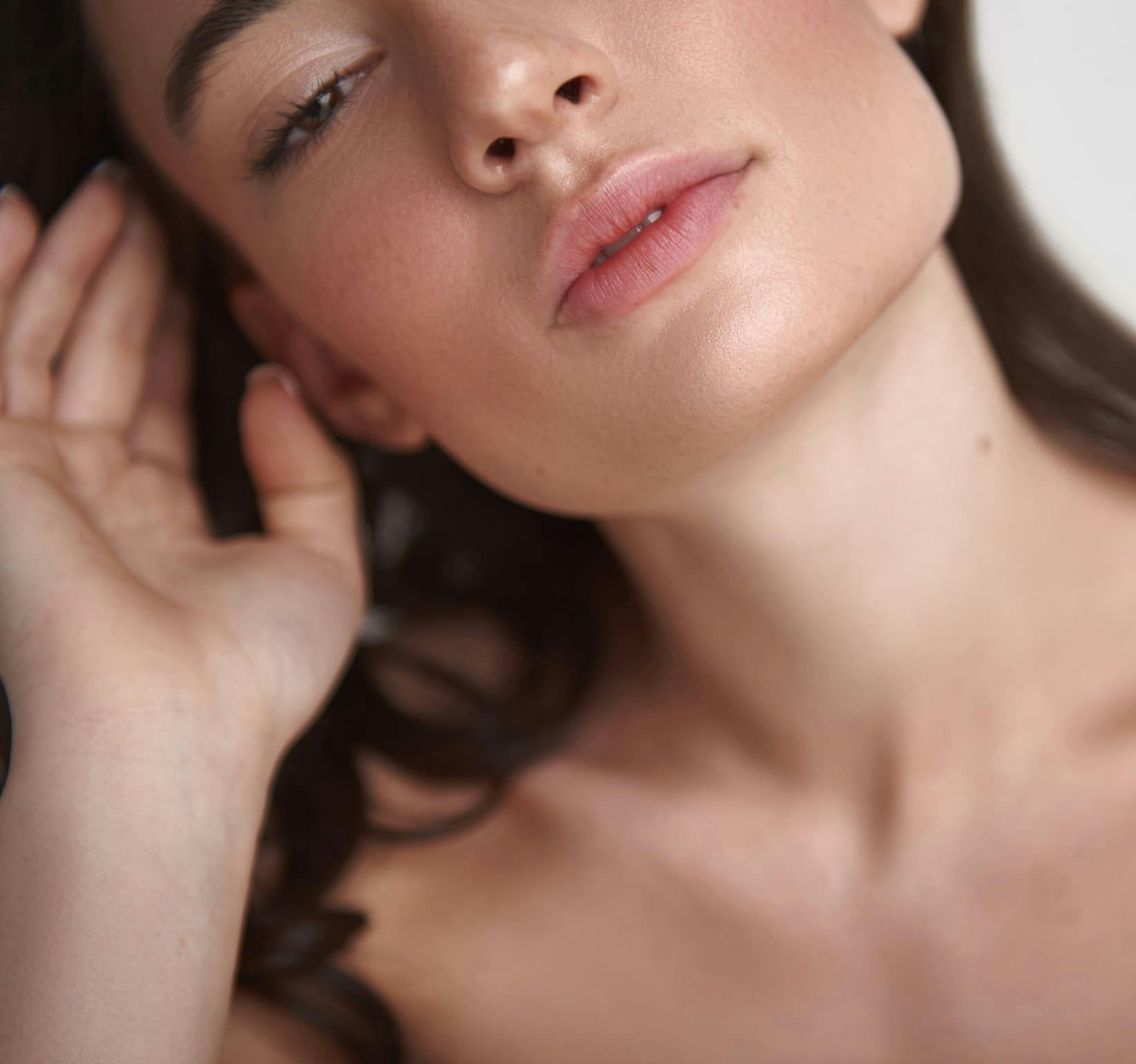 close up of woman's jaw as she moves her hair back