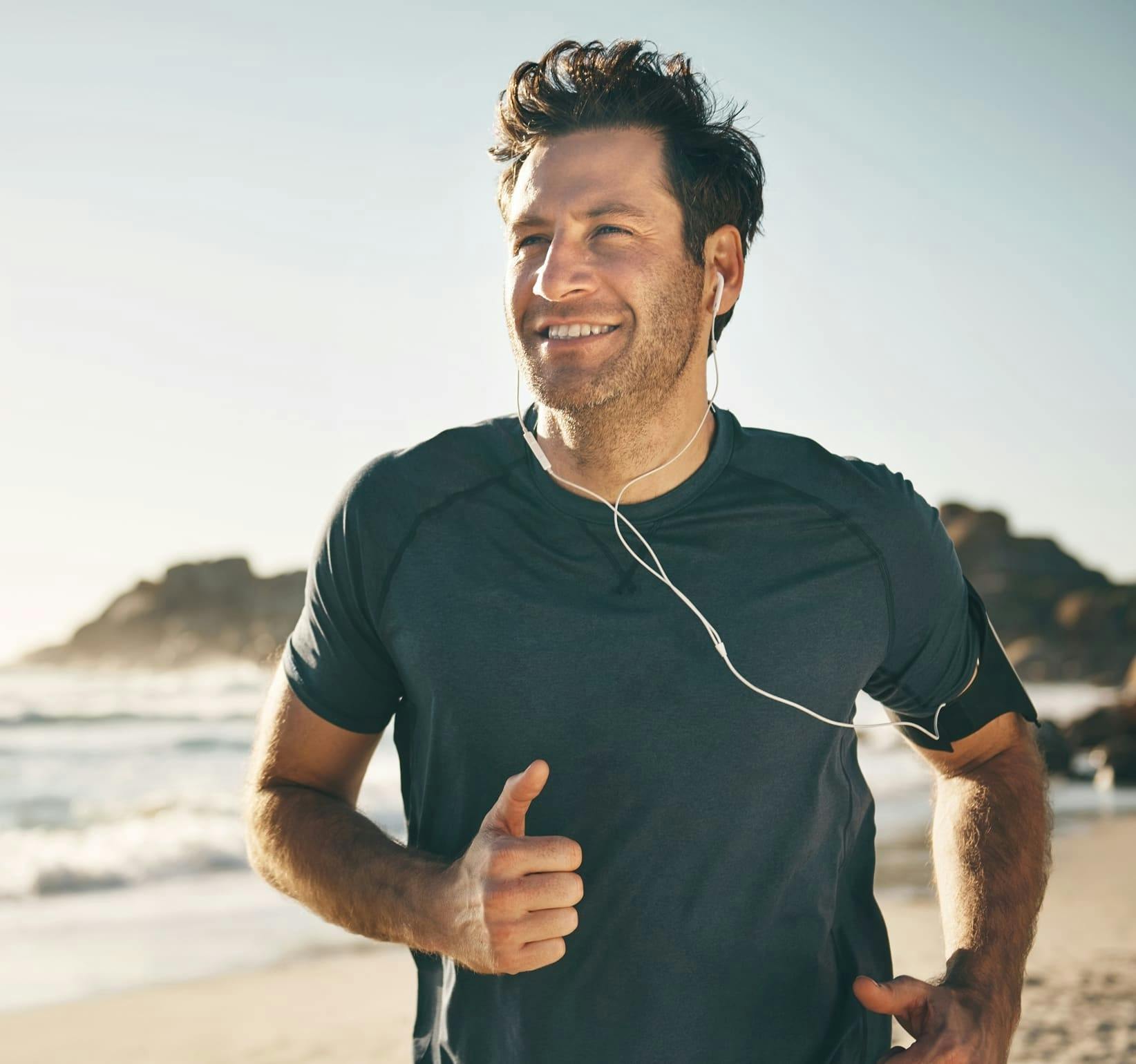 man jogging on the beach with earbuds in