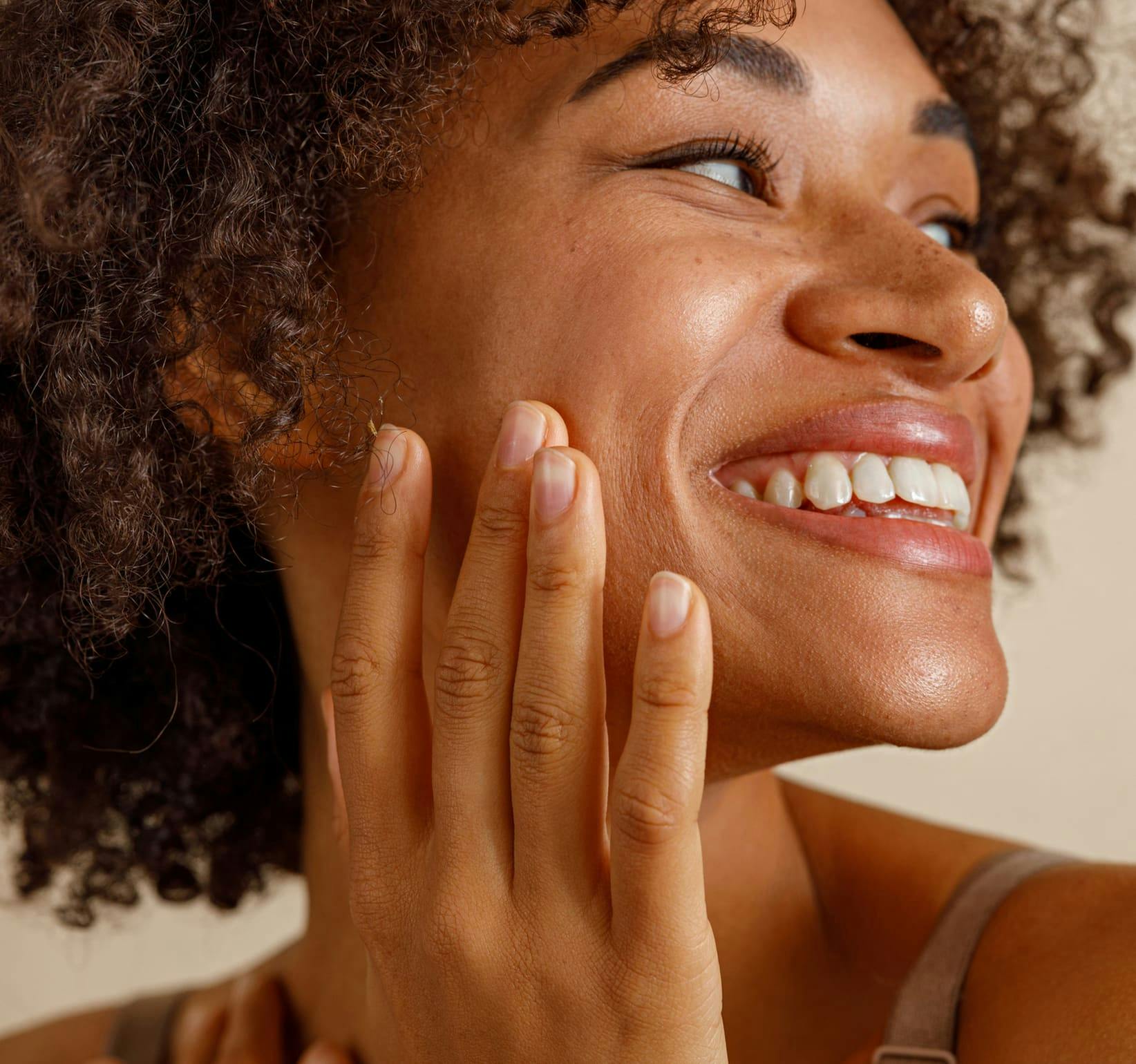 woman with afro touching her cheek and smiling