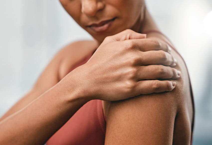 woman gripping her shoulder