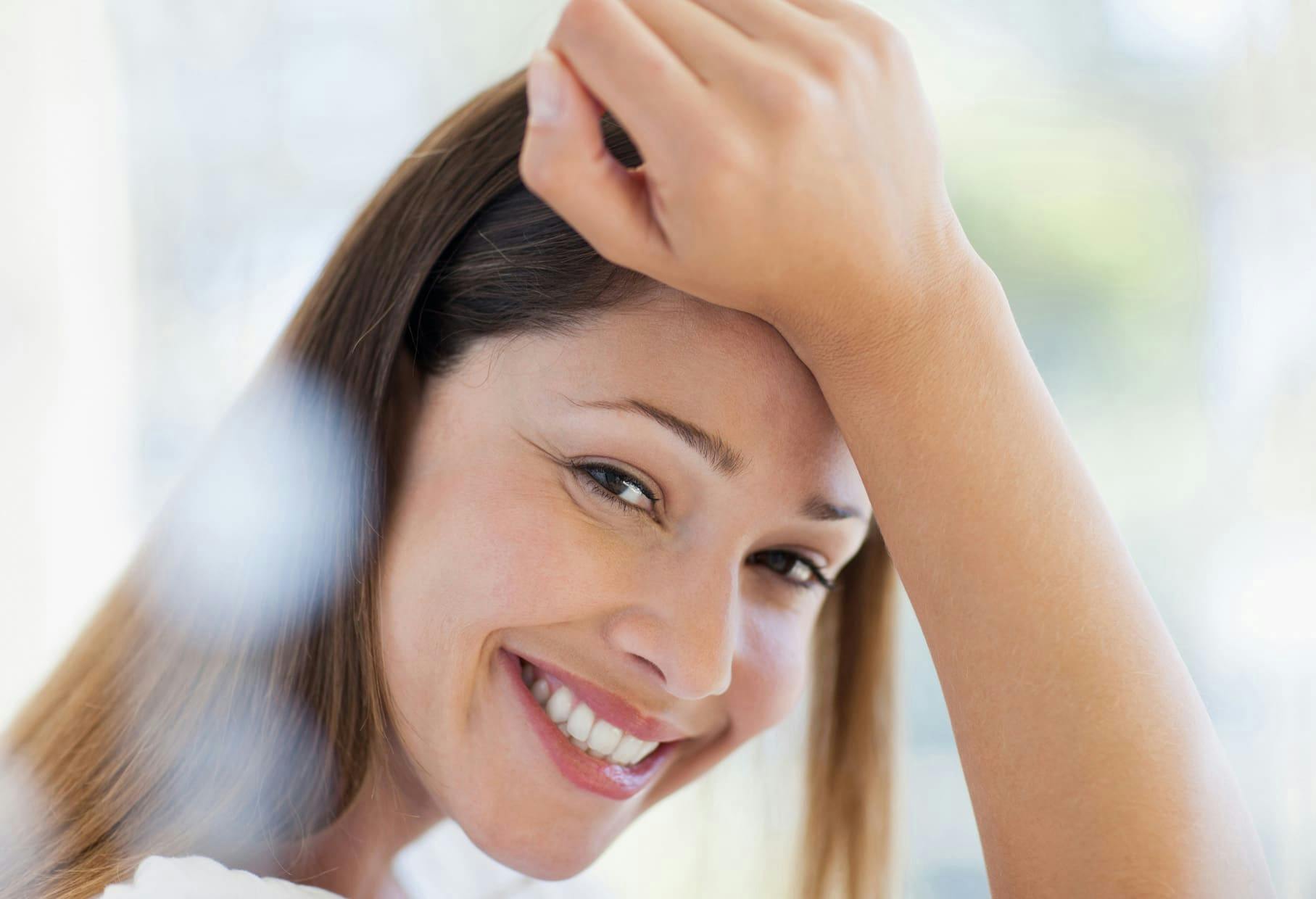 woman smiling with her wrist on her forehead
