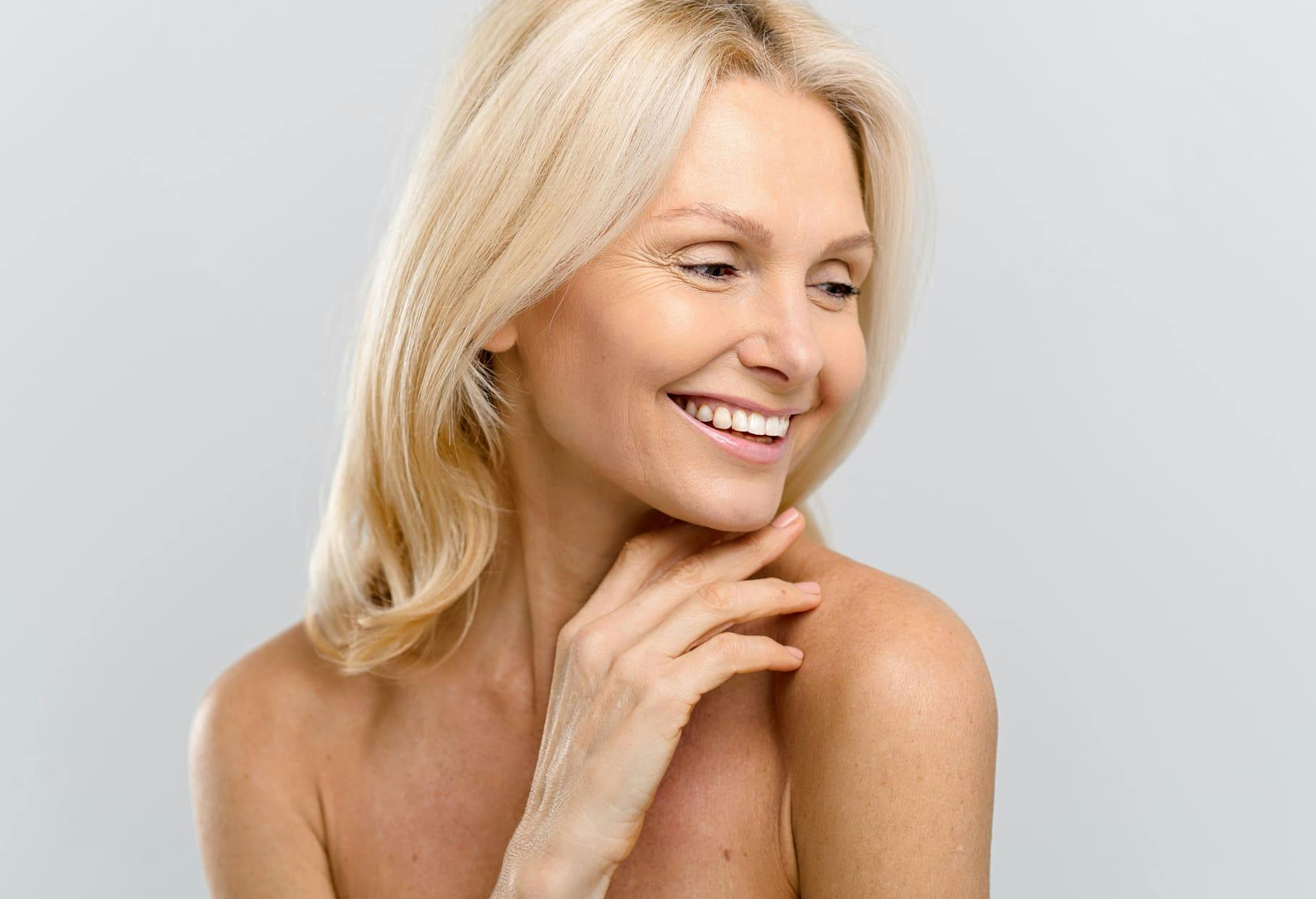 woman with blonde hair smiling with her hand under her chin
