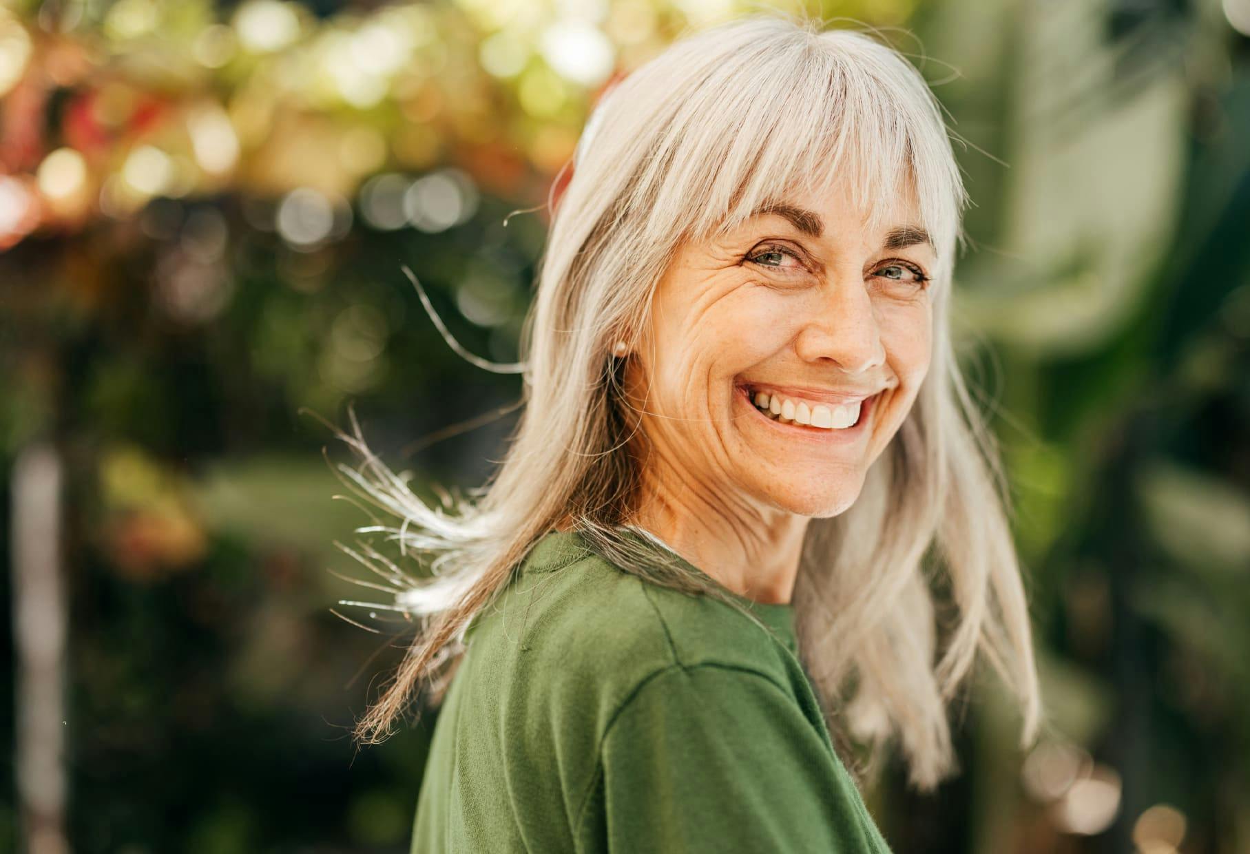 older woman smiling outside in green shirt