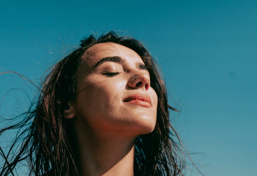 woman with her eyes closed tilting her head up in the sky