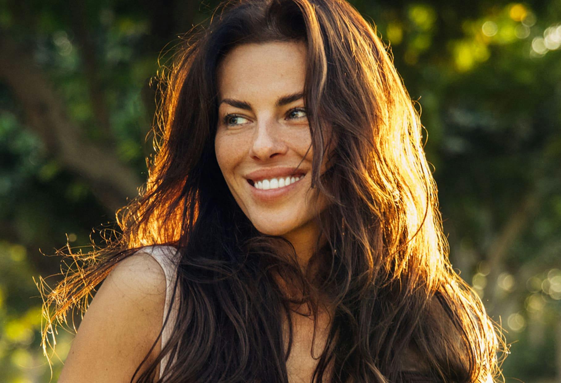 woman with long brown hair smiling outside