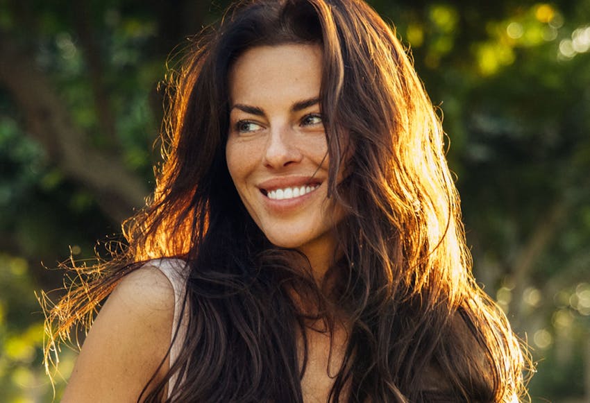 woman with long brown hair smiling outside