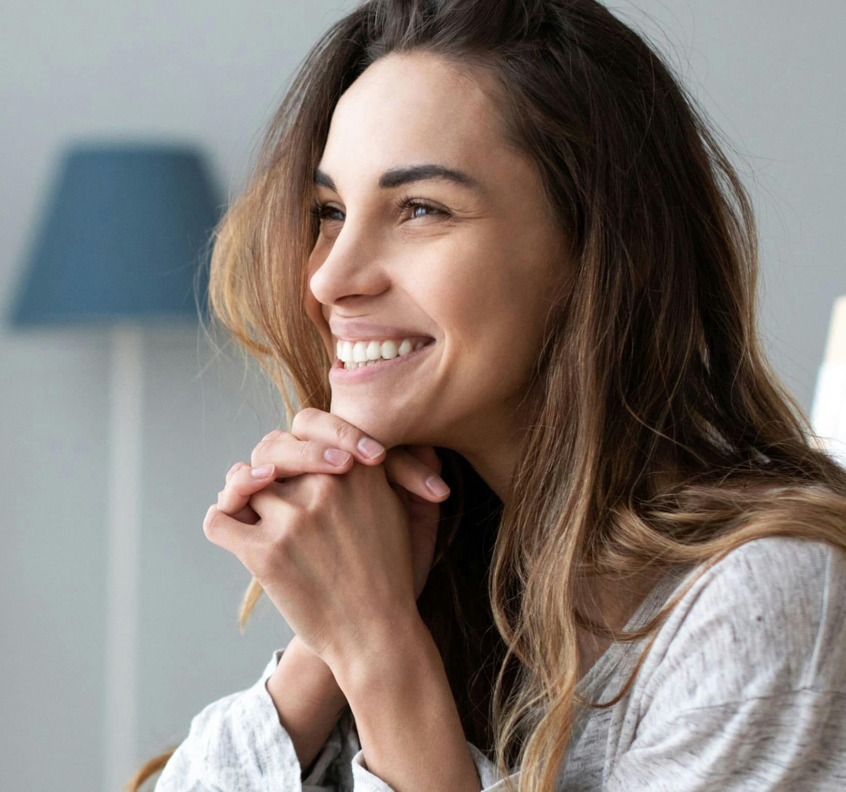 woman smiling with her hands against her chin