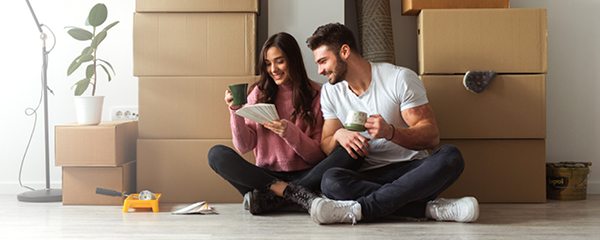 Young couple sitting on the floor in front of moving boxes in their new home