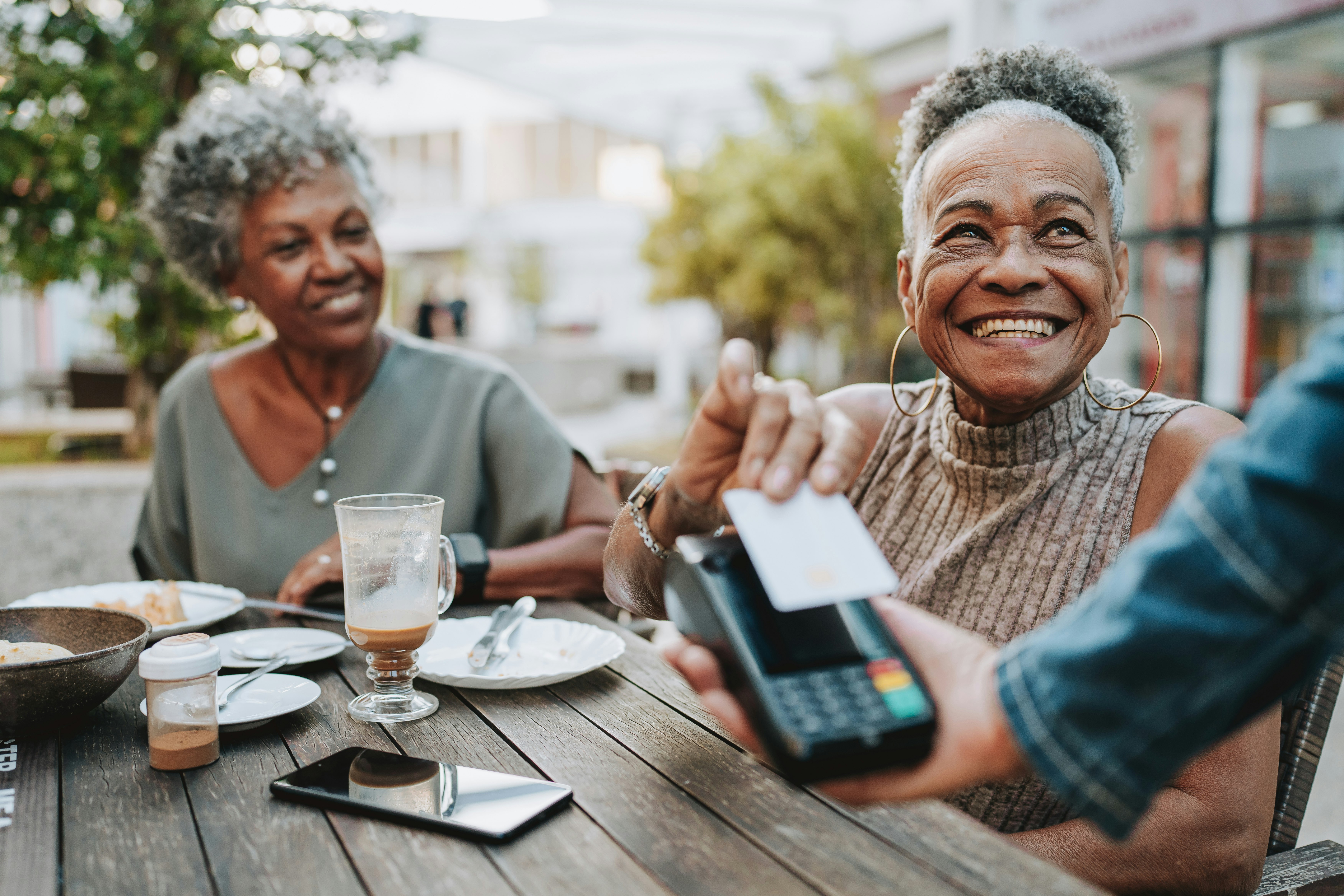 Friends paying for dinner at an outdoor table.