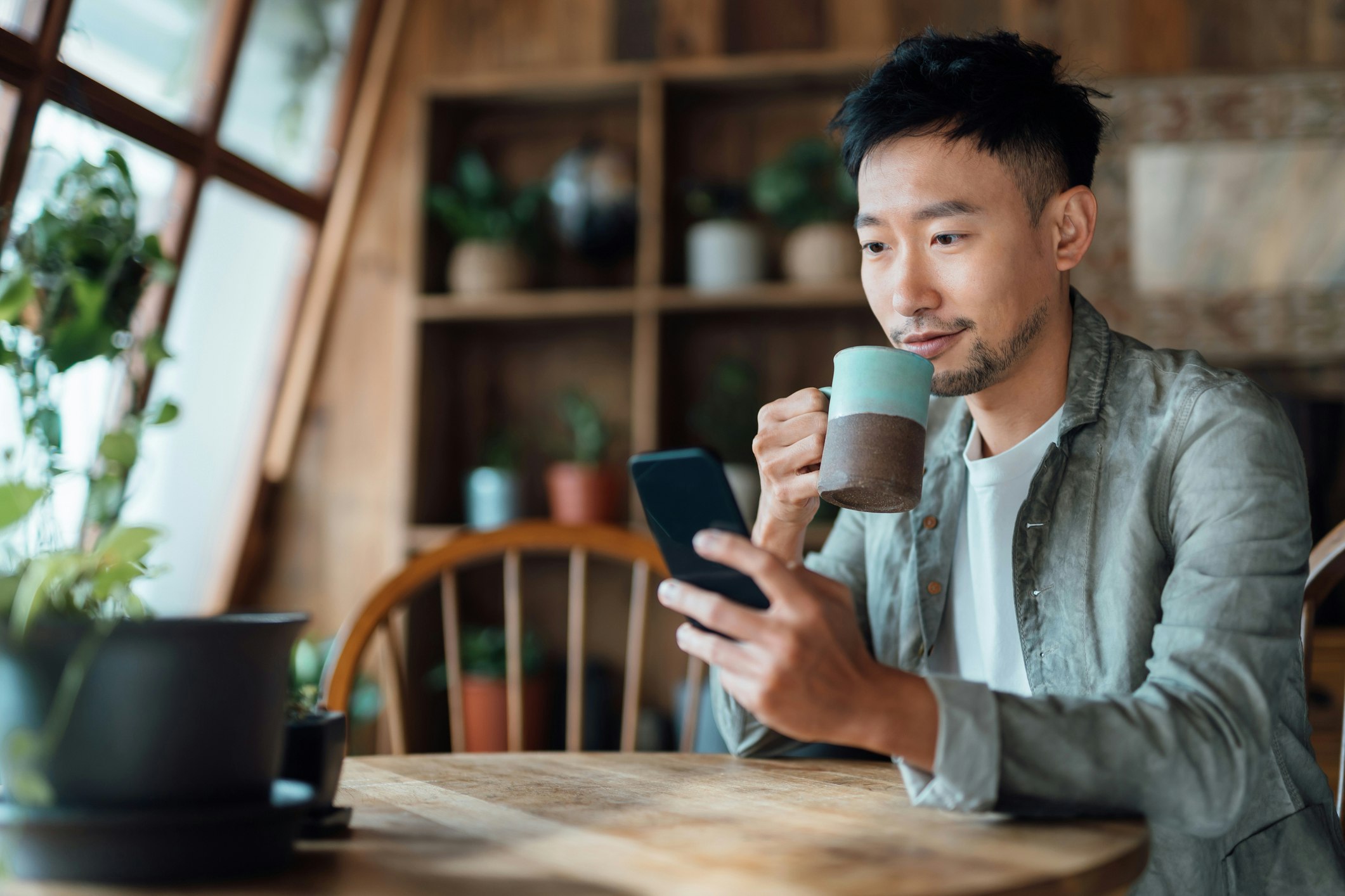 man drinking coffee and looking at phone