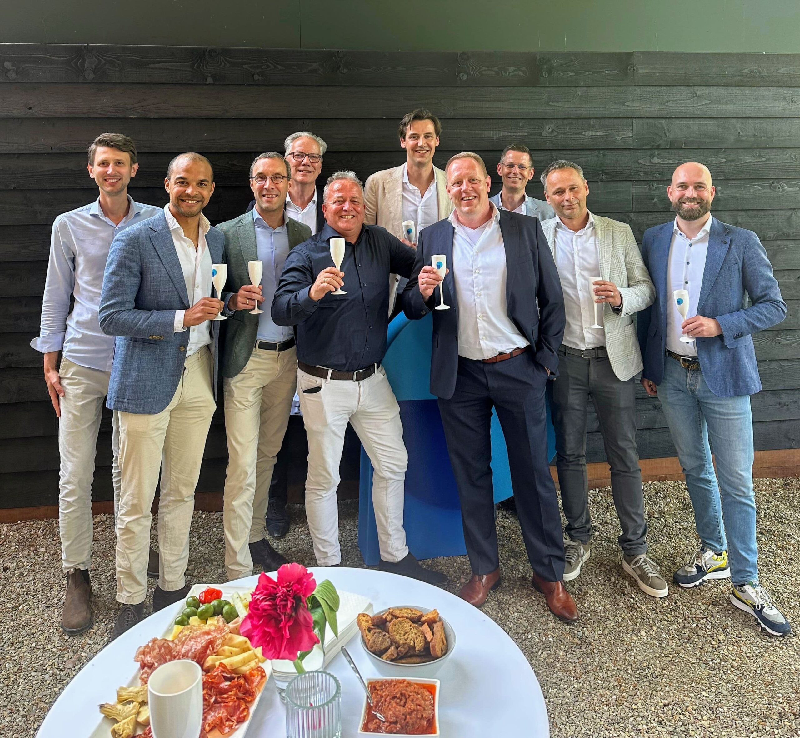 Groepsfoto waarop personen een glazen champagne vast hebben