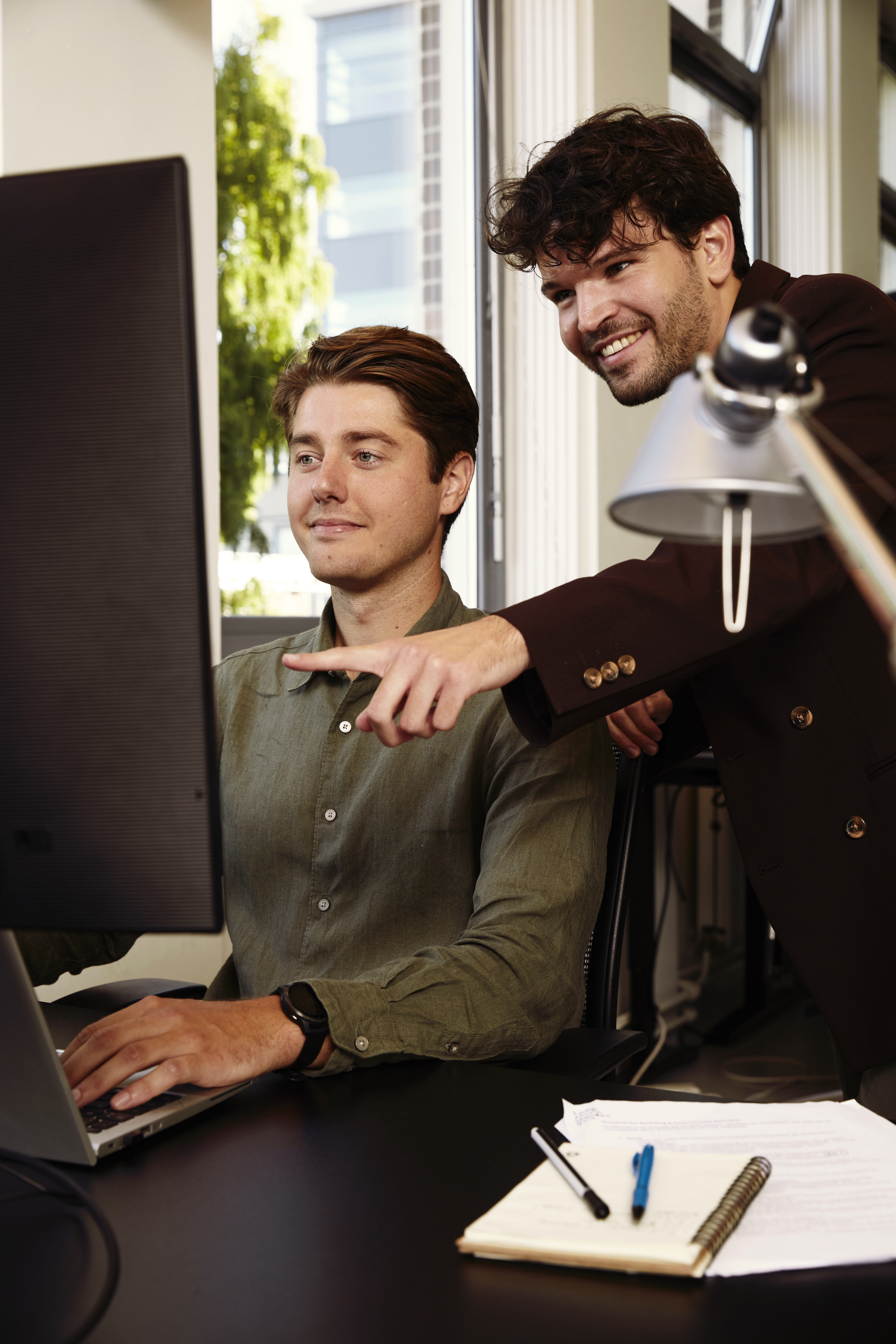 Twee collega's achter een computerscherm.