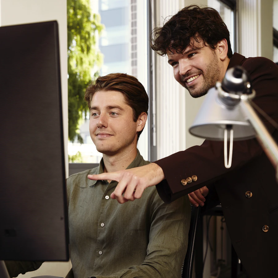 Twee collega's achter een computerscherm.