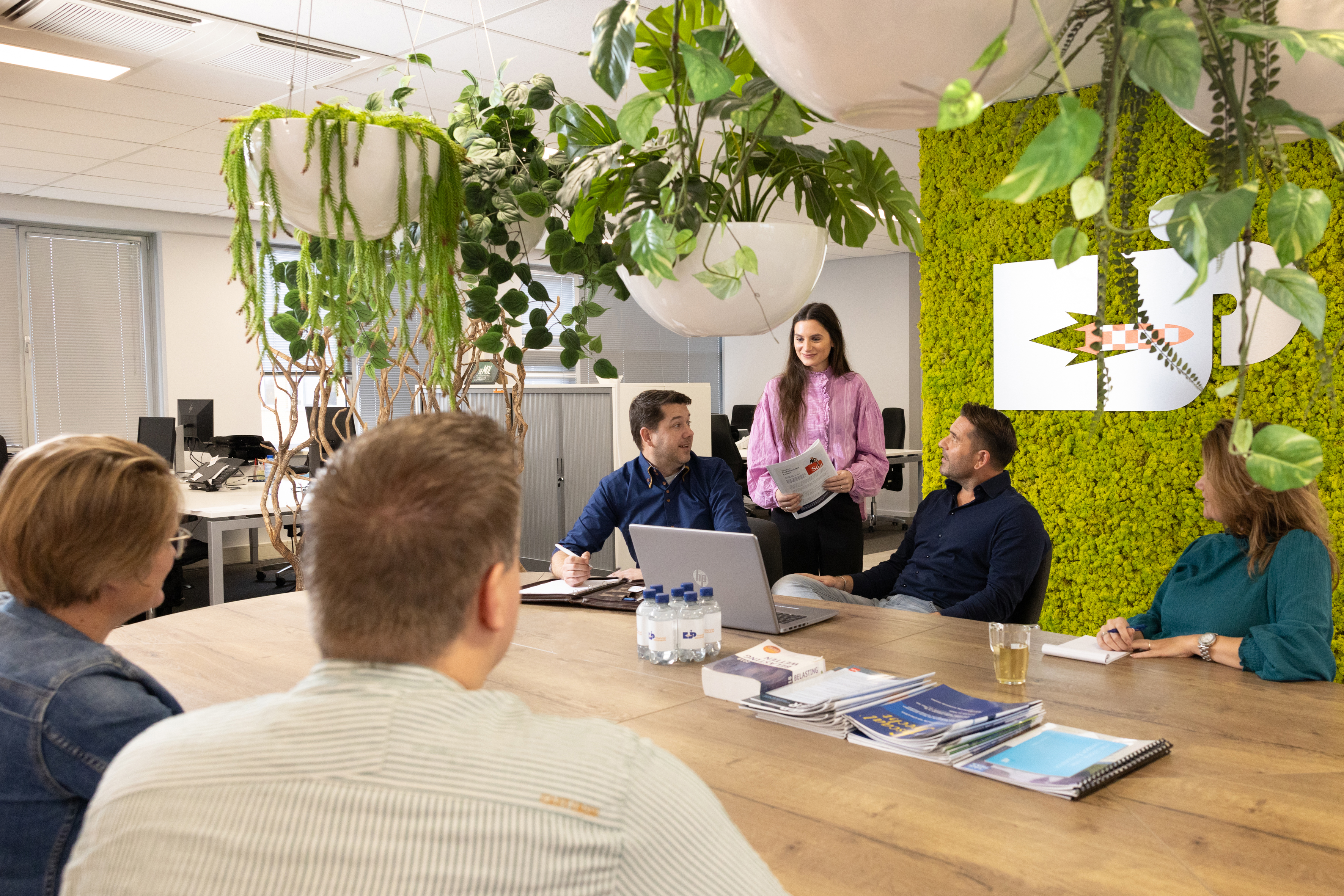 Zes personen zitten rond een tafel, ze zijn met elkaar in gesprek.