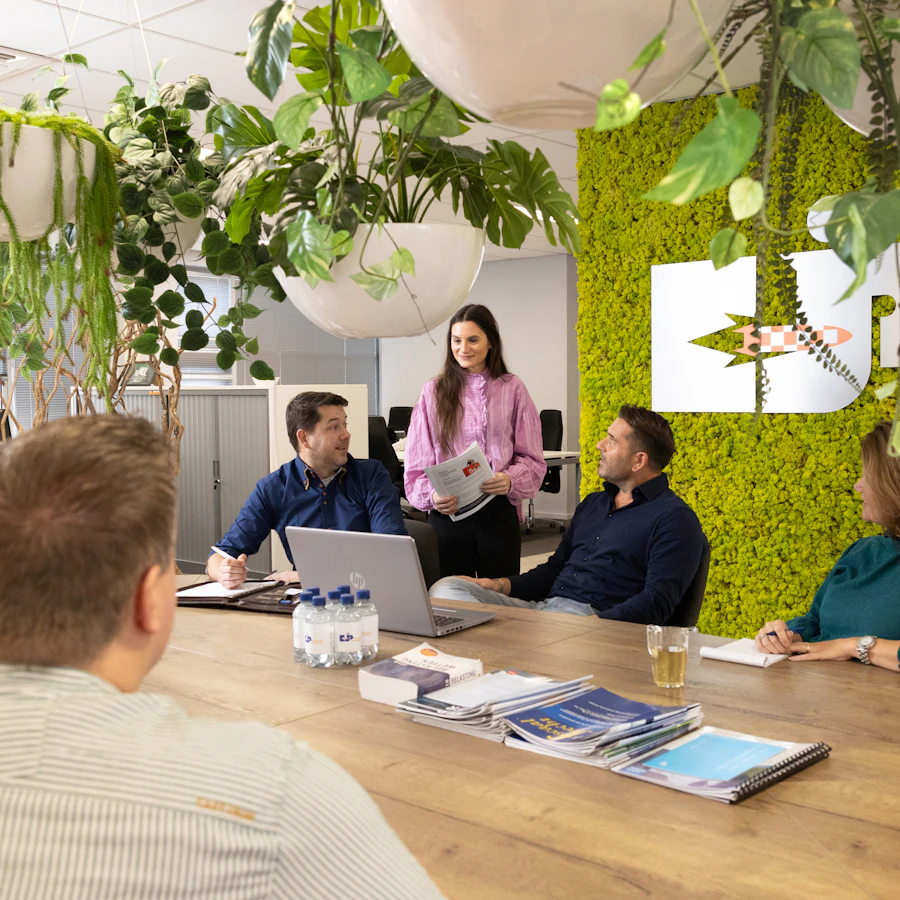 Zes personen zitten rond een tafel, ze zijn met elkaar in gesprek.