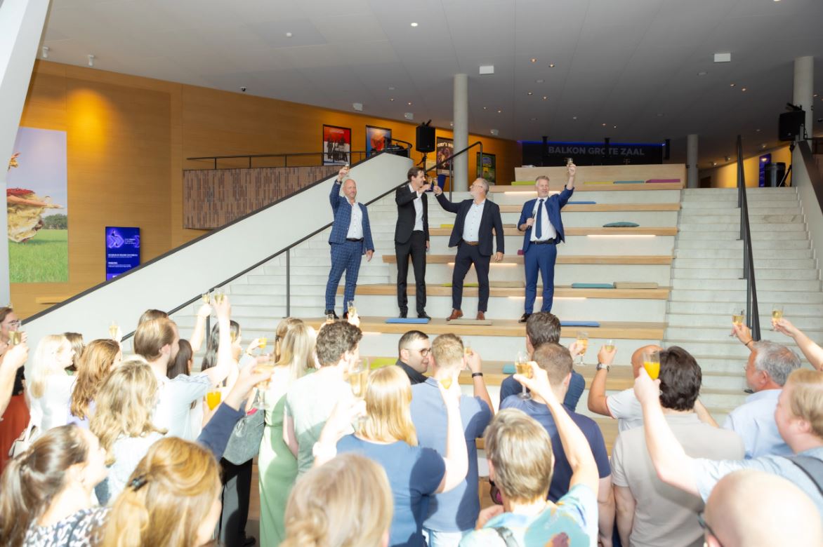 Dealfoto van PIA. Groep mensen heft een glas champagne.