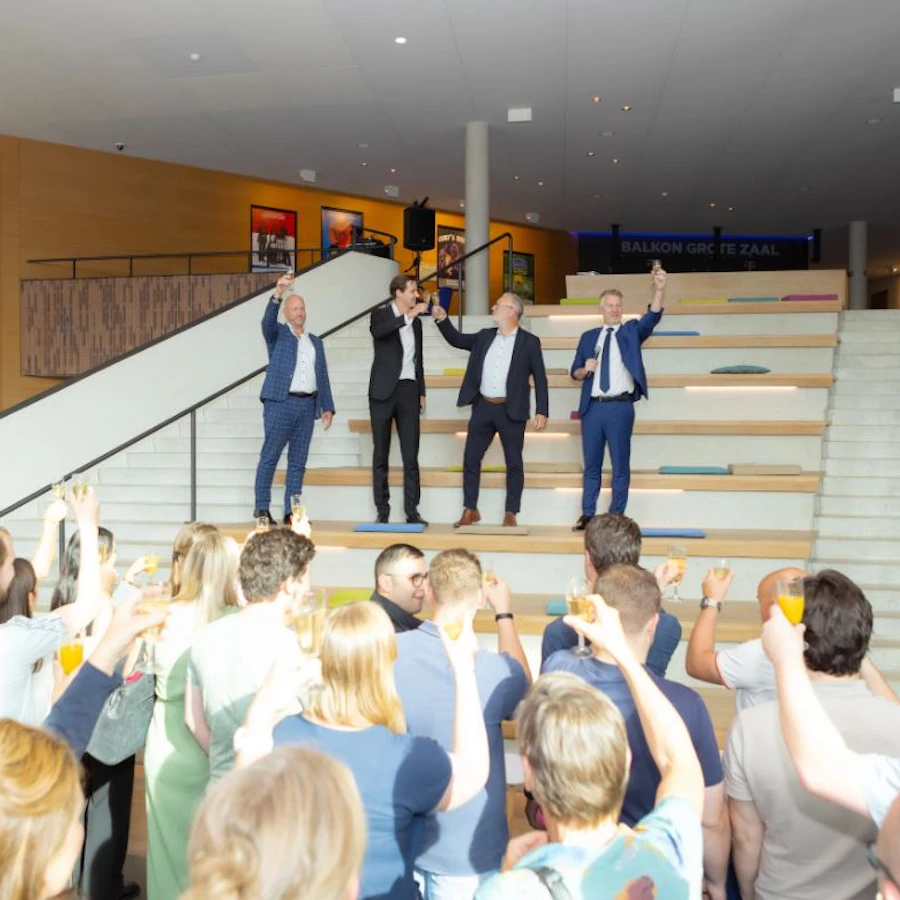 Dealfoto van PIA. Groep mensen heft een glas champagne.