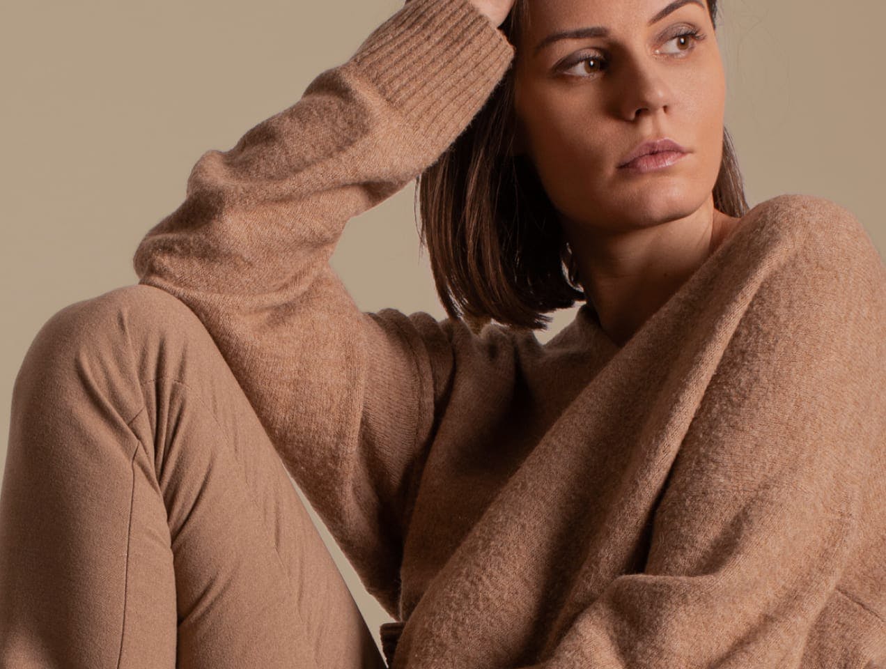 Woman in sweater with hand on head