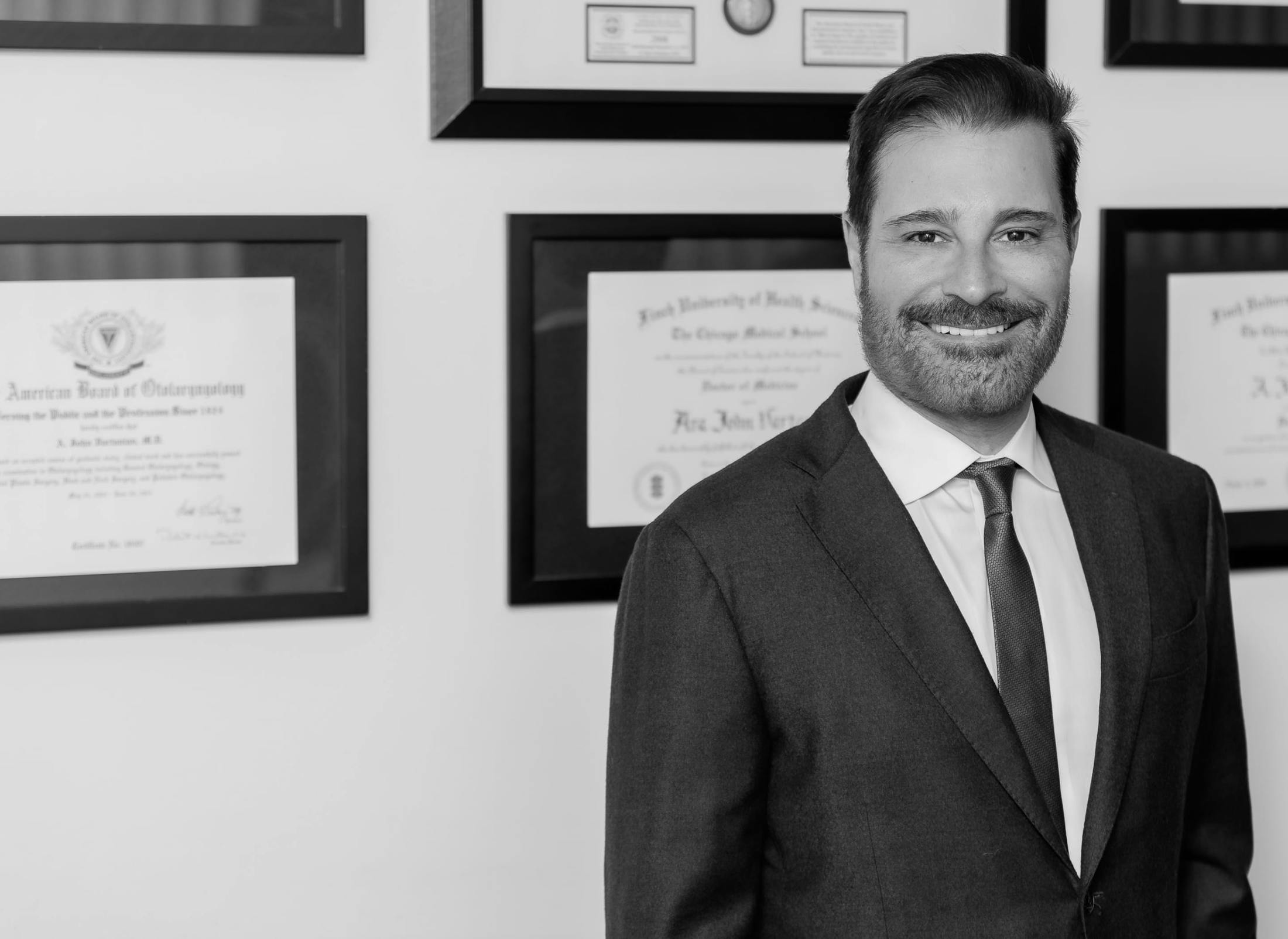 Dr. Vartanian in a suit in front of his plaques