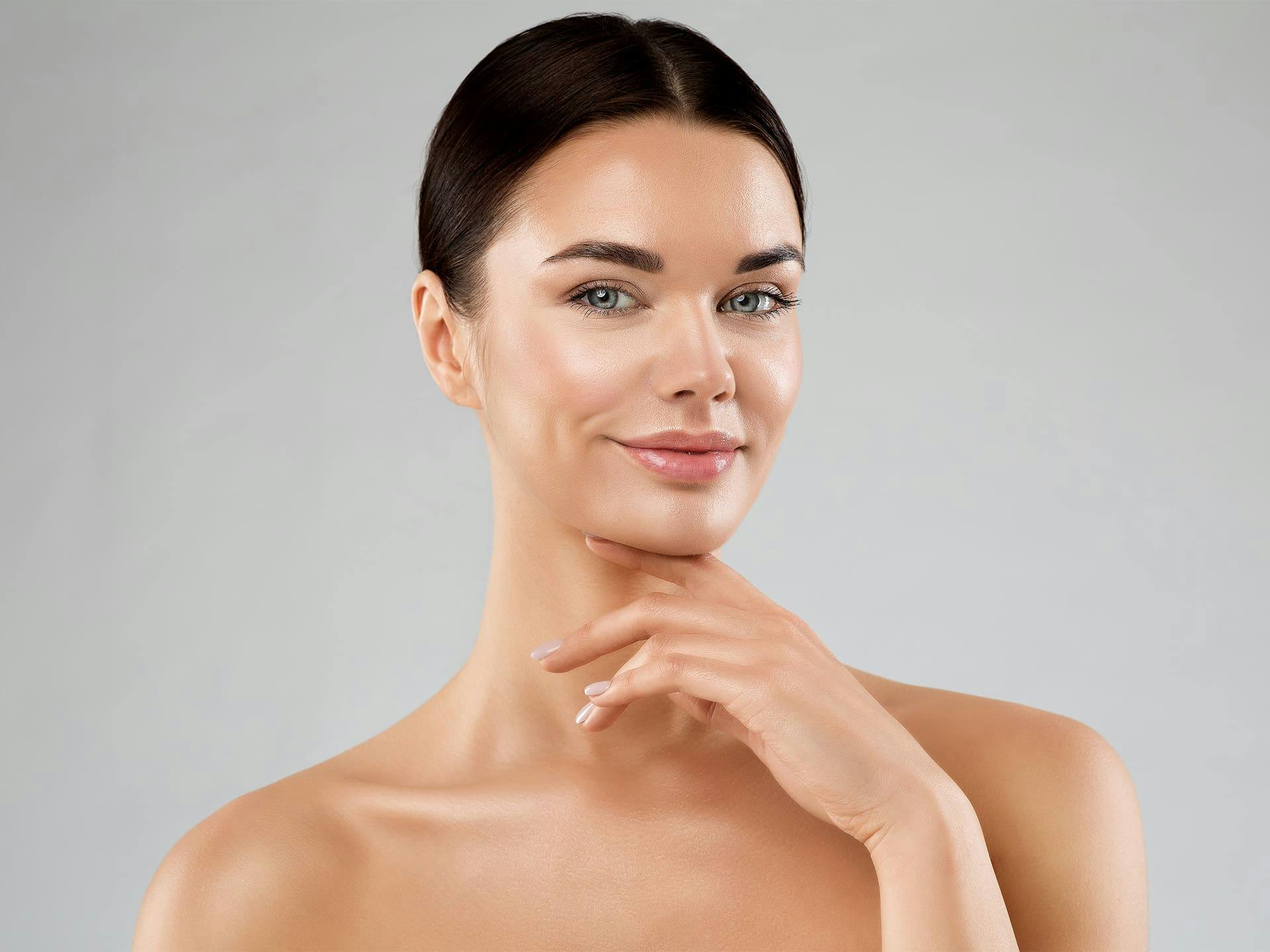 woman with her hair tied back and her hand under her chin