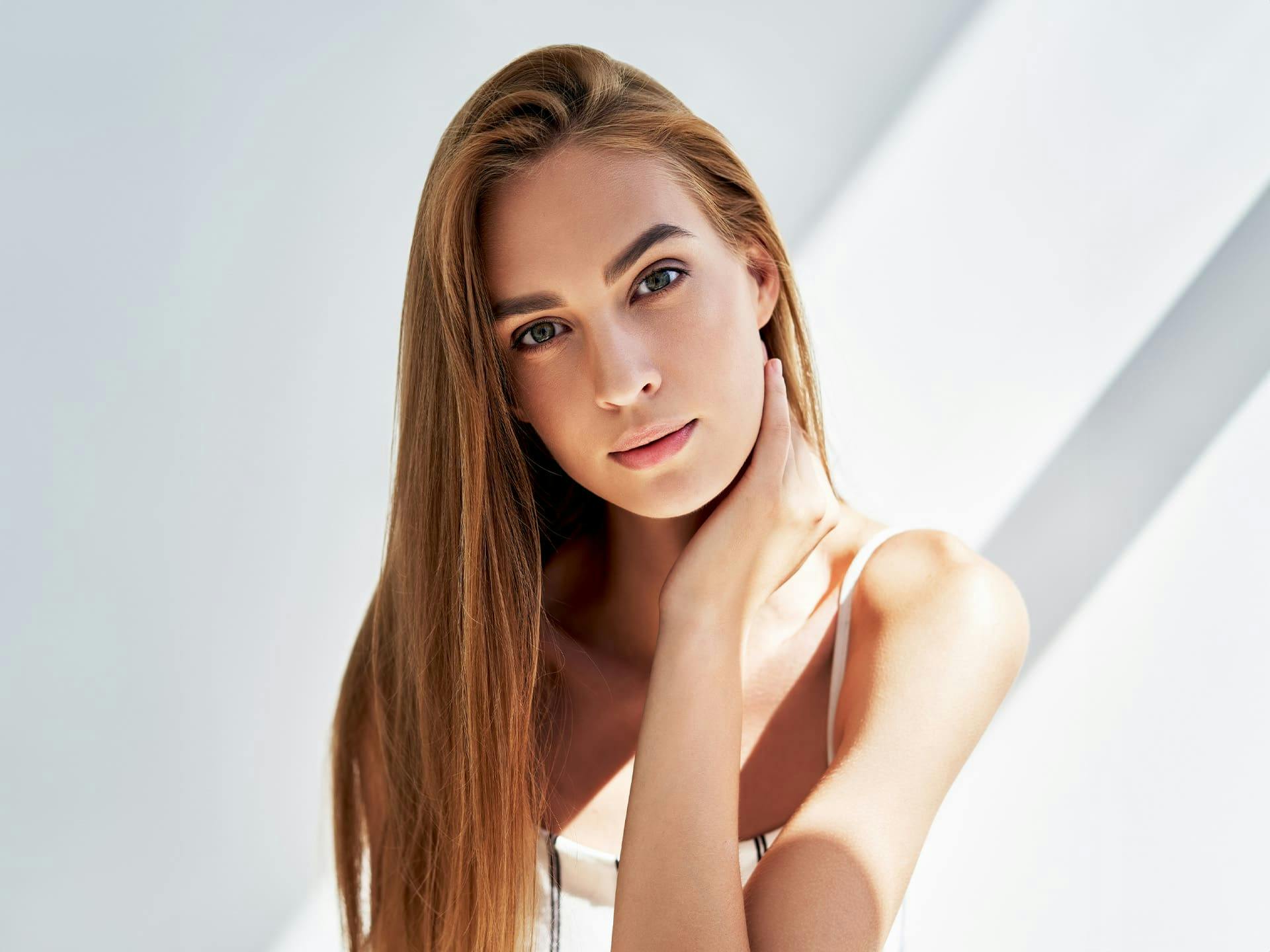woman with long straight hair and her hand on her neck