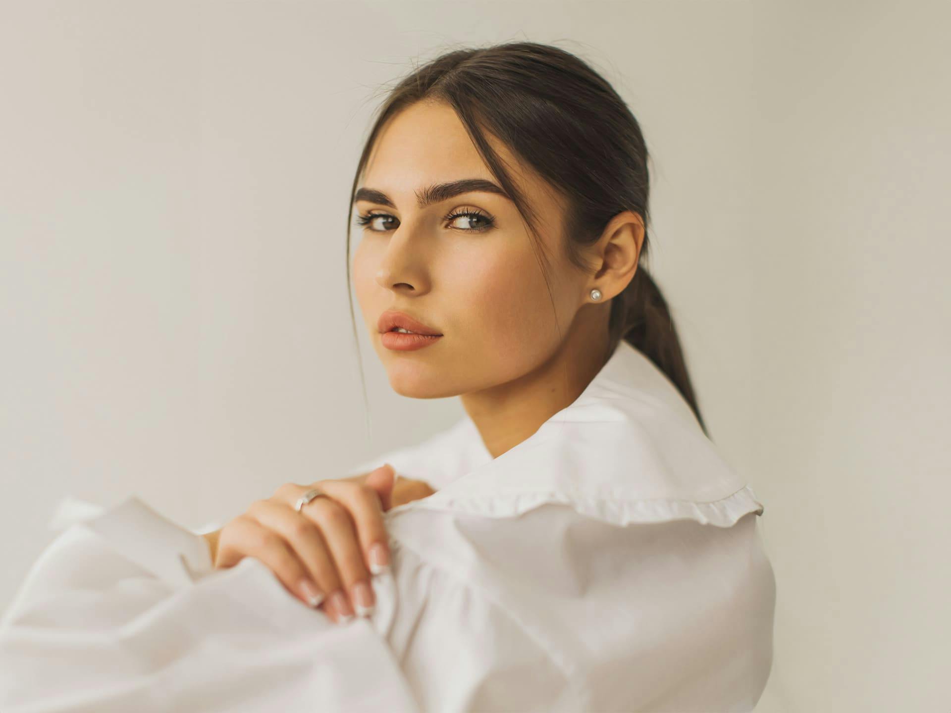 woman in white formal attire with her hair in a slick back ponytail