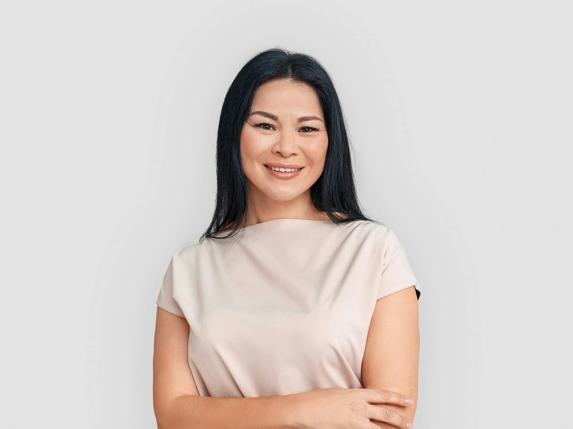 asian woman smiling with her arms crossed