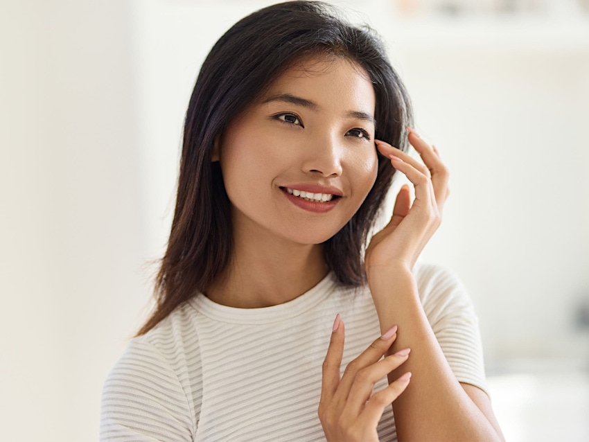 woman smiling with her finger near her temple