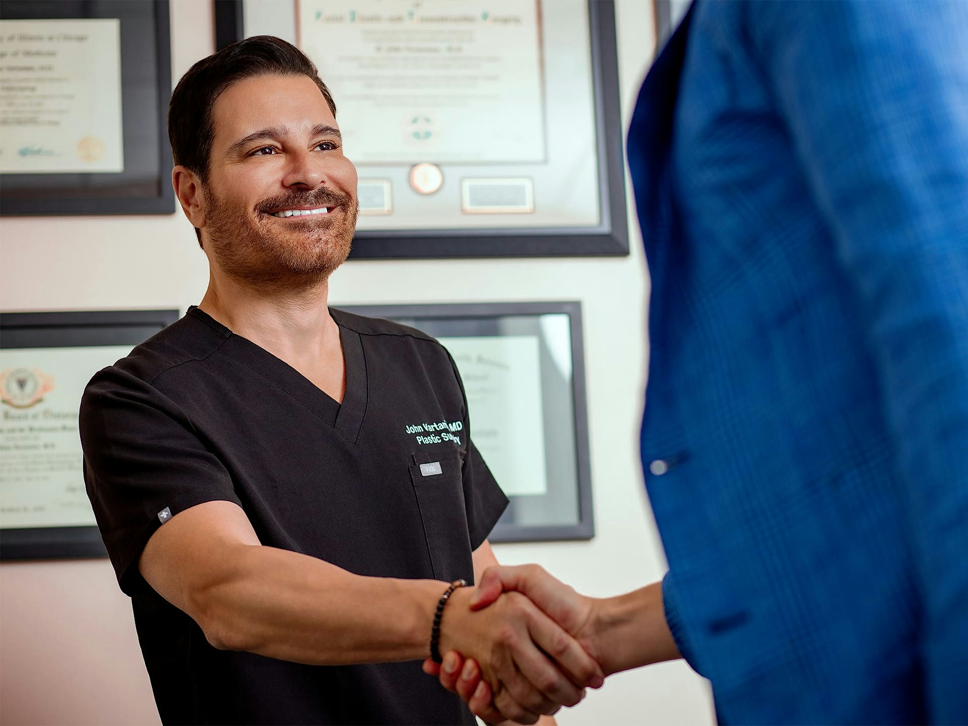 Dr. John Vartanian smiling and shaking hands with a person