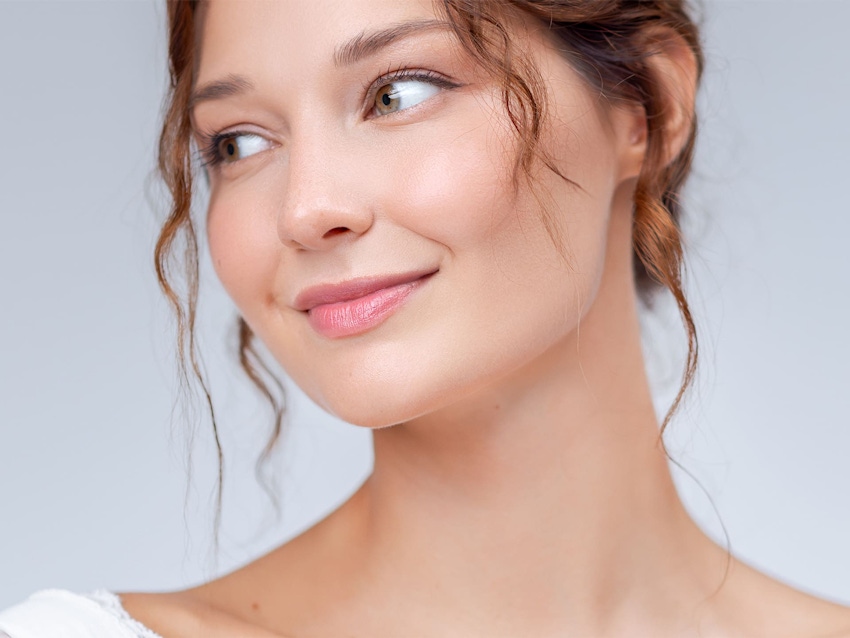 woman with wavy hair smiling and looking to the left