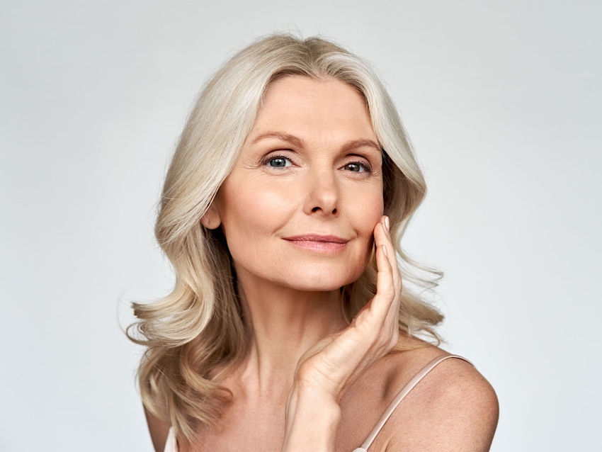 older woman smiling with her hand on her cheek