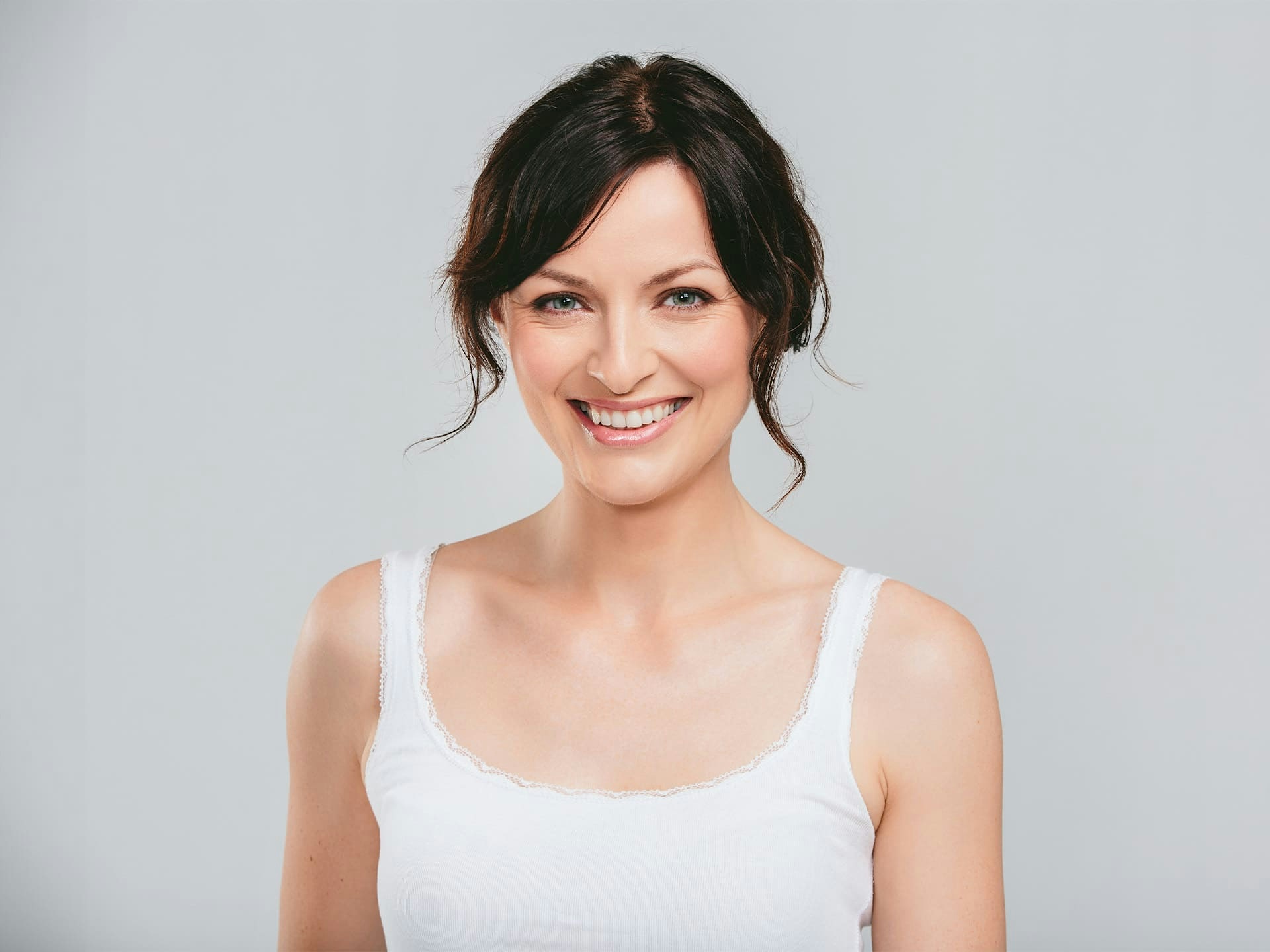 woman smiling forward with white tanktop