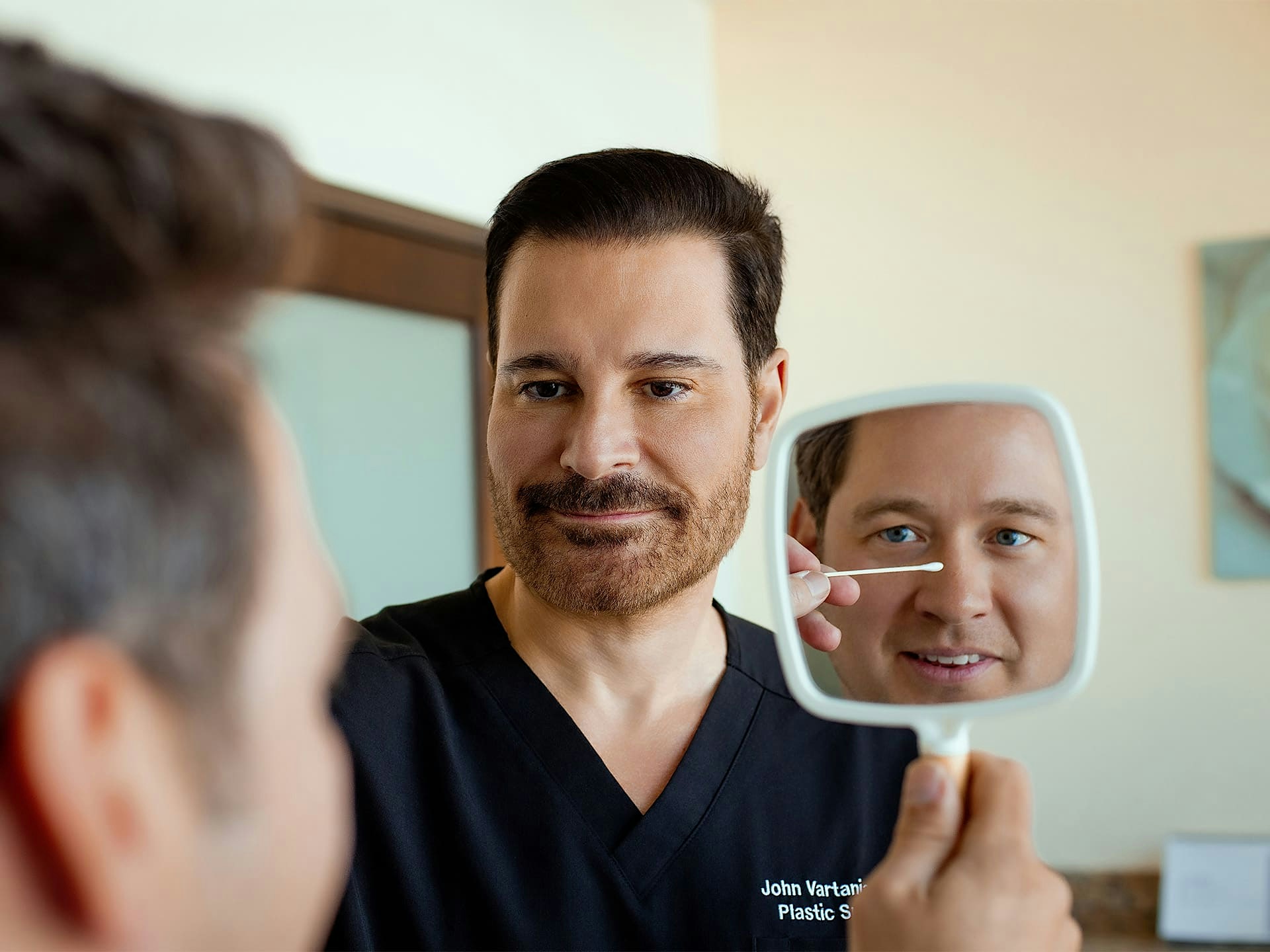 Dr. John Vartanian looking at male patient's nose