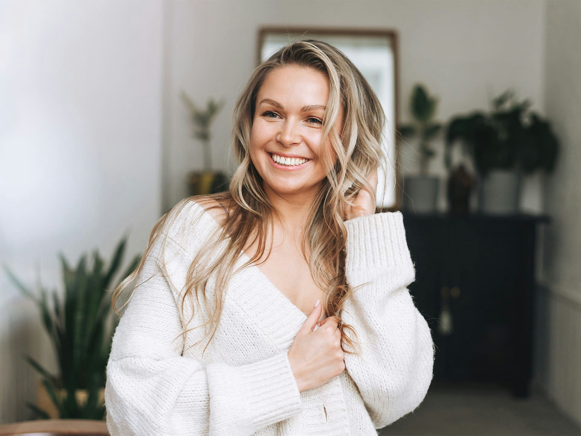 blonde woman smiling with over-sized sweater on