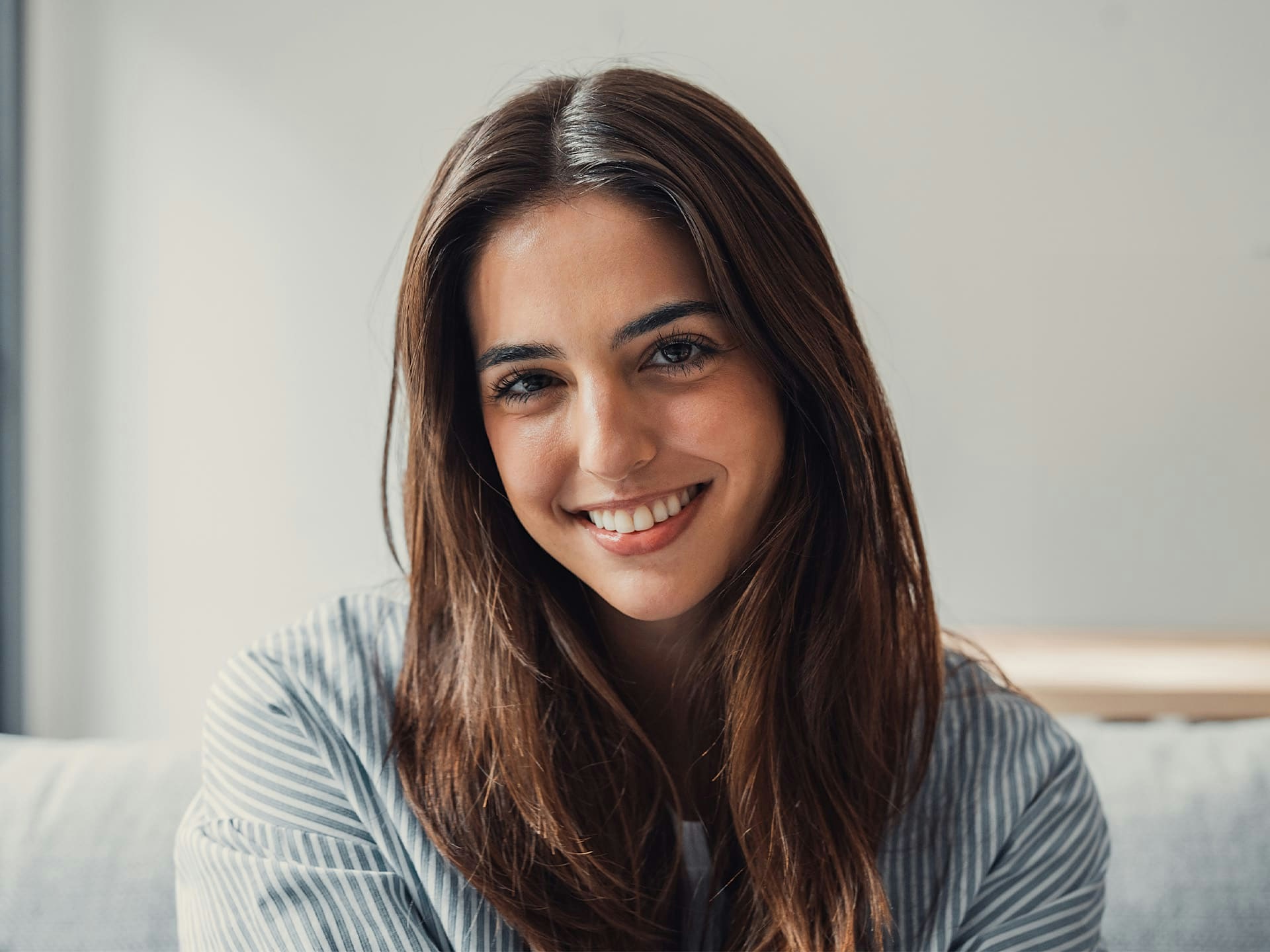 woman sitting on couch smiling with striped shirt on