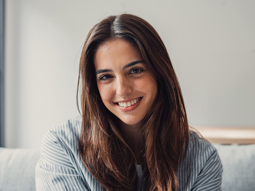 woman sitting on couch smiling with striped shirt on