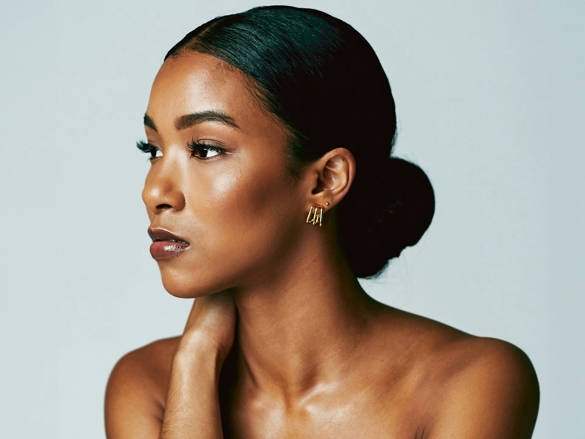 african-american woman with low bun in her hair looking to the left with her hand on her neck