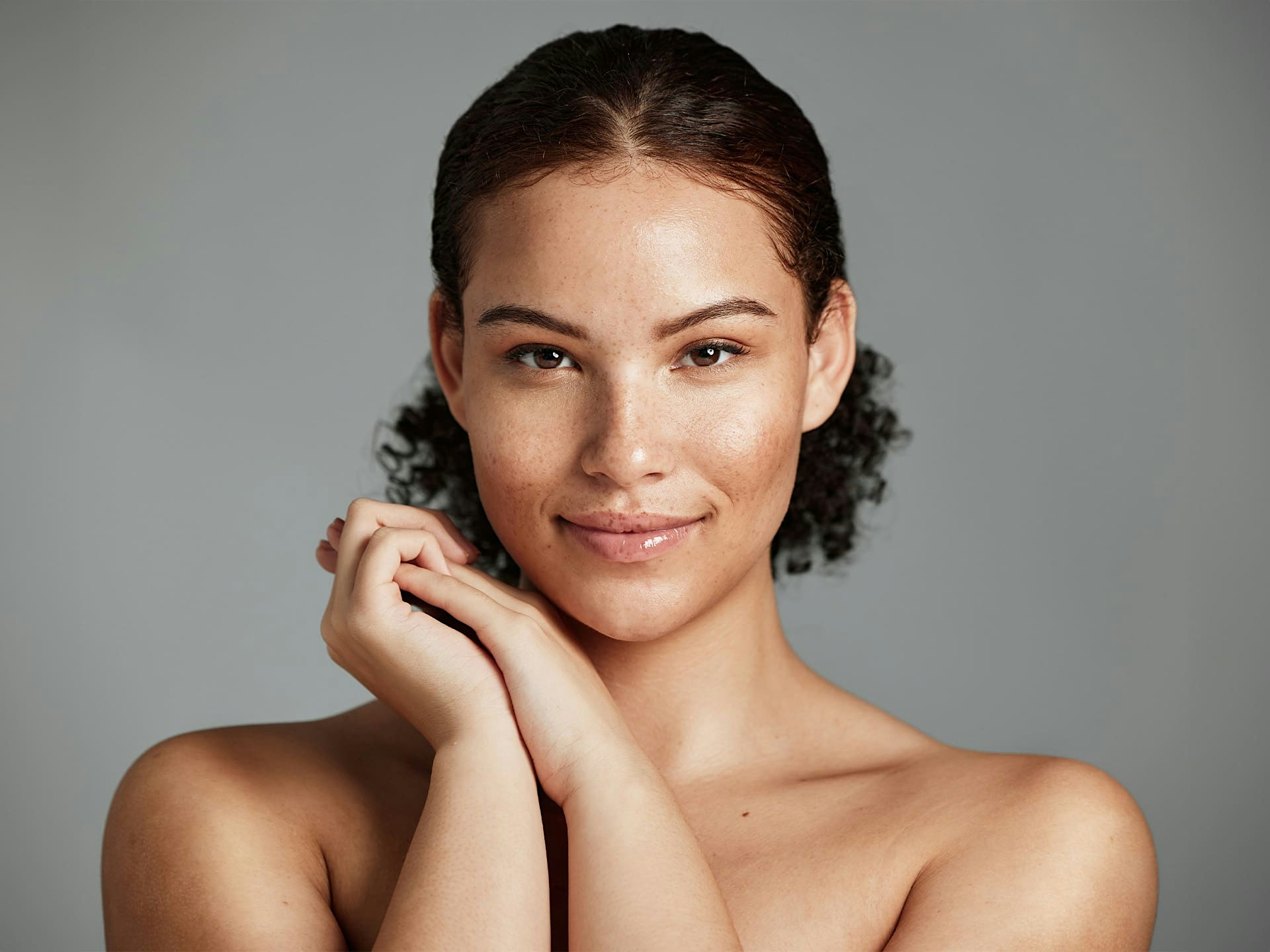 woman looking forward with her hands together near her face