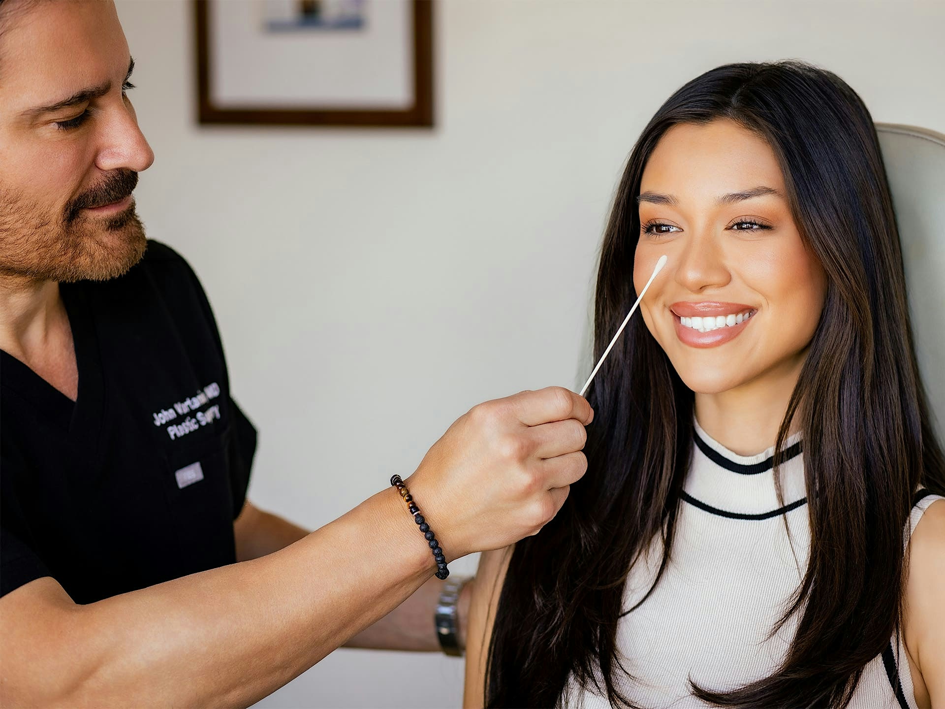 Dr. John Vartaian looking at female patient's nose bridge
