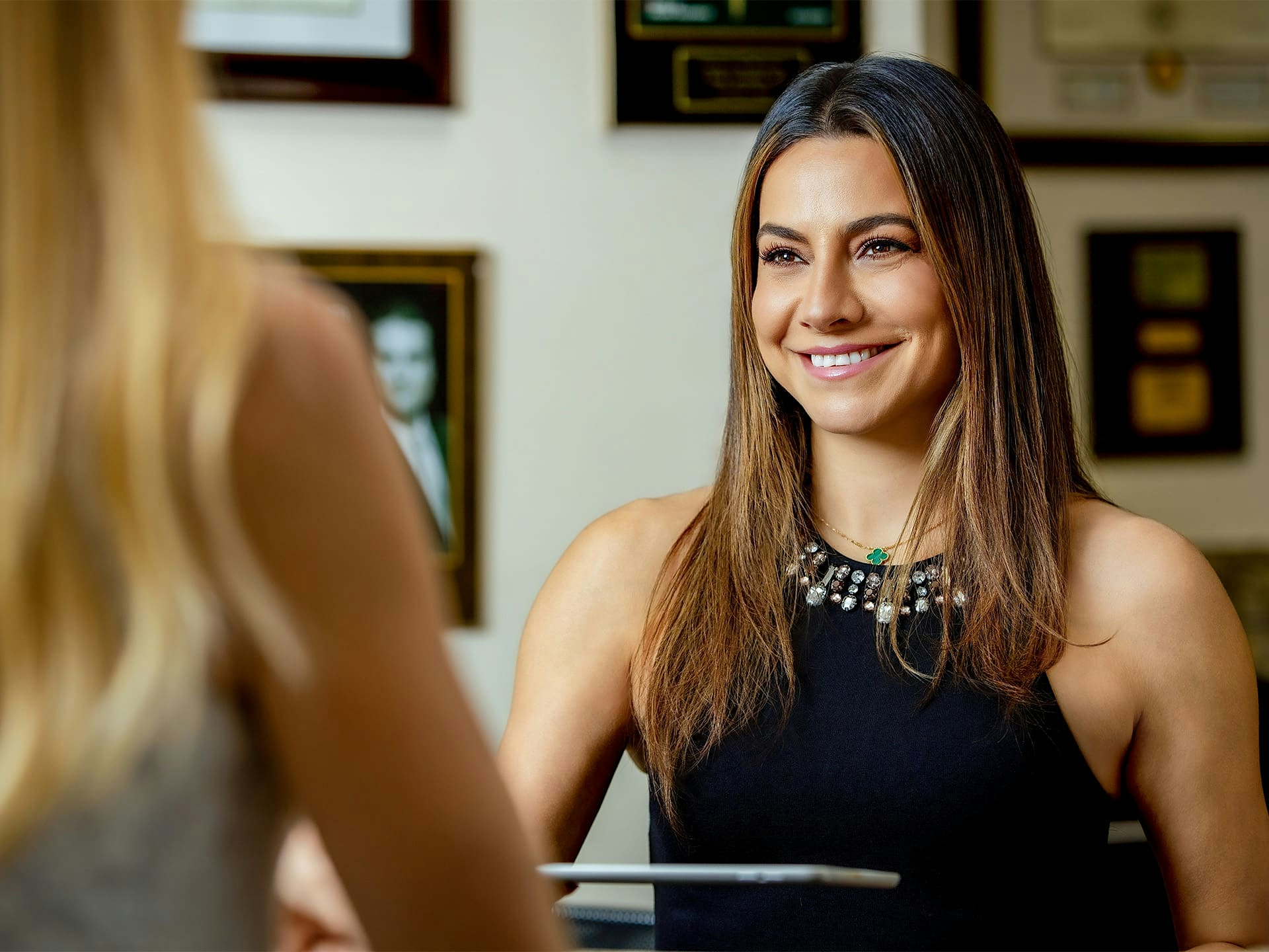 woman smiling while handing ipad to female patient