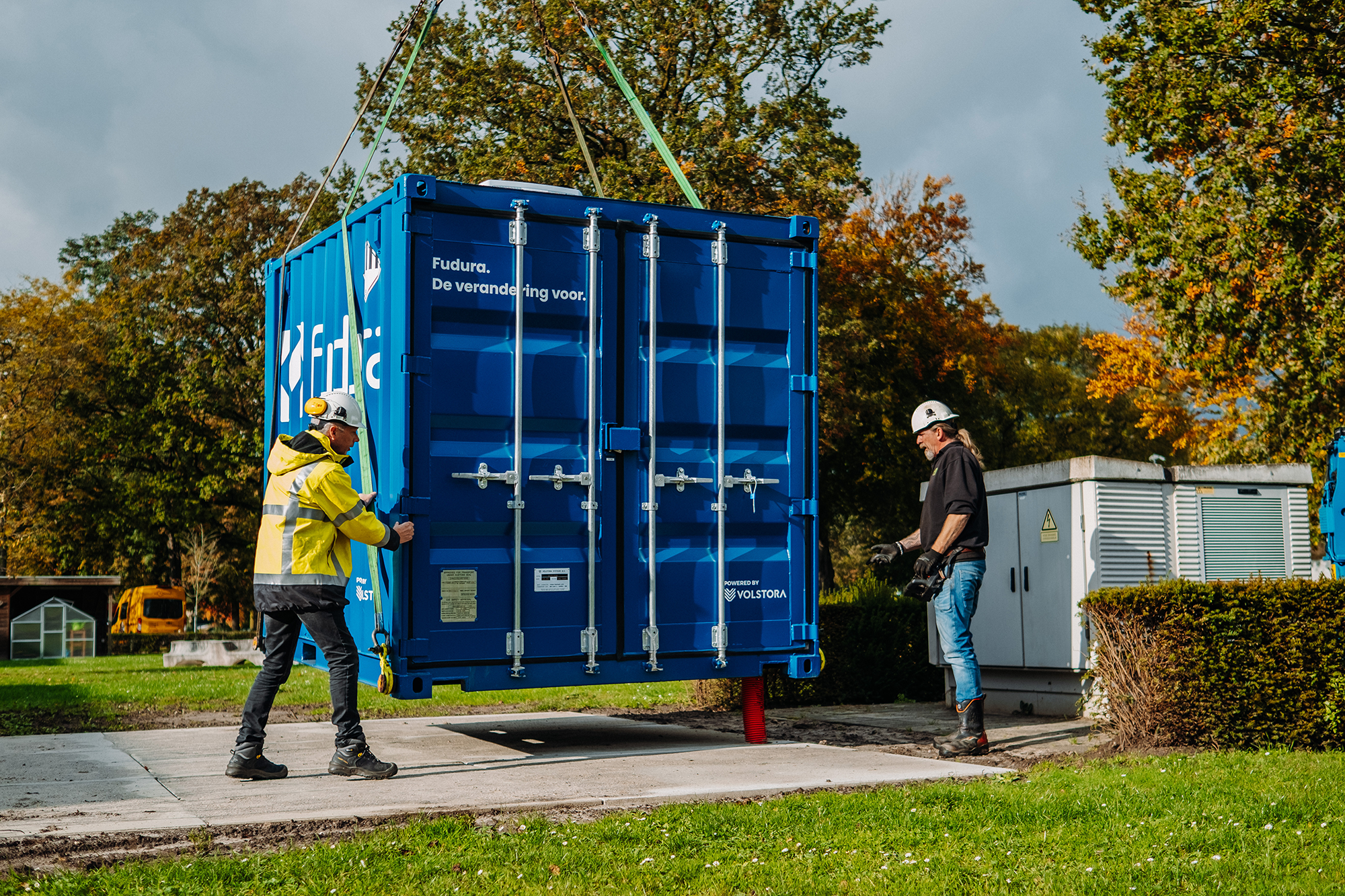 Mensen aan het werk met een container waar een batterij in zit.