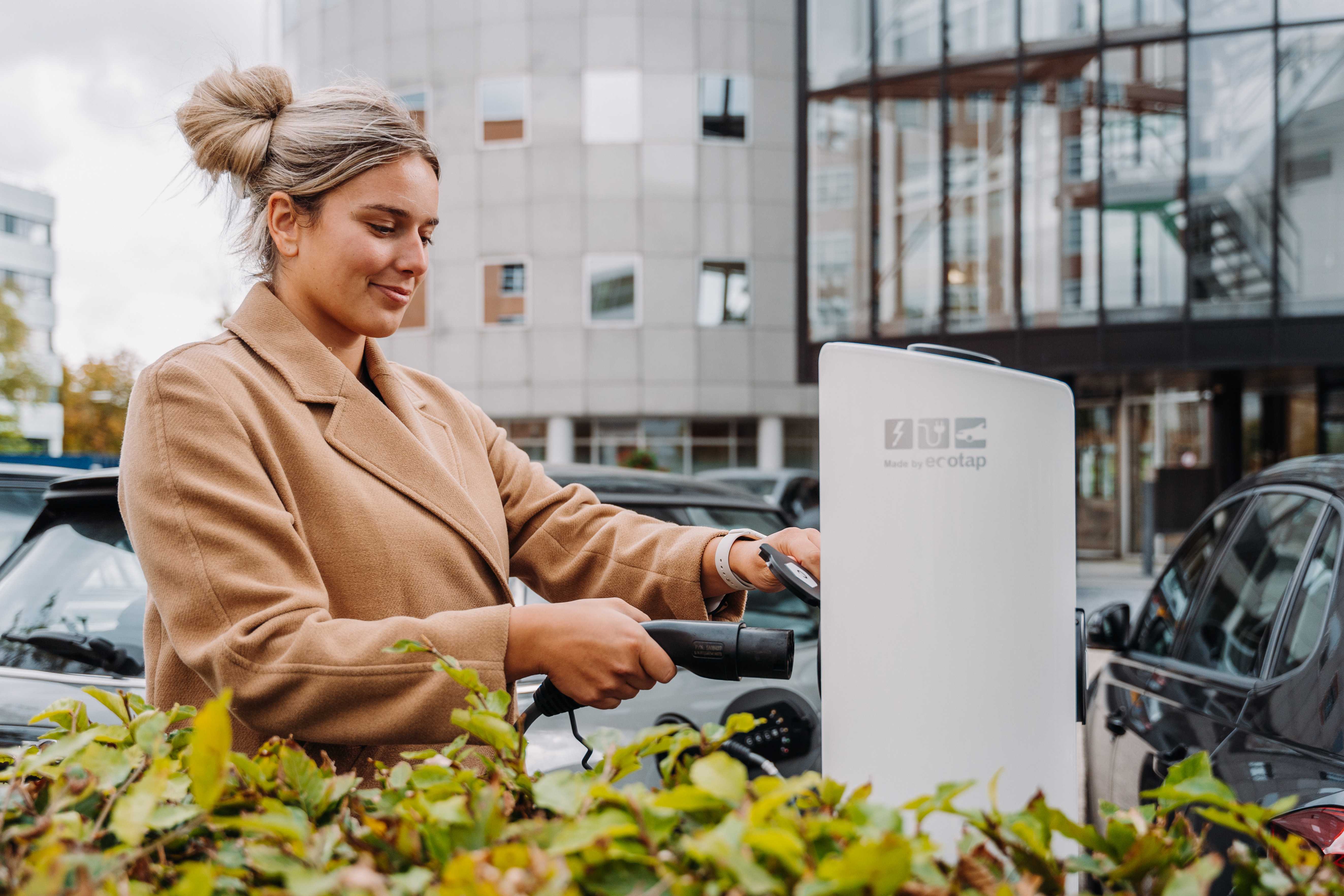Vrouw plugt oplader in oplaadpaal