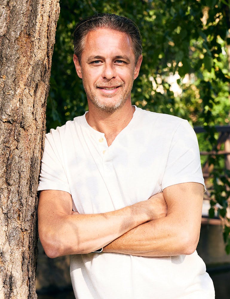 man leaning against a tree