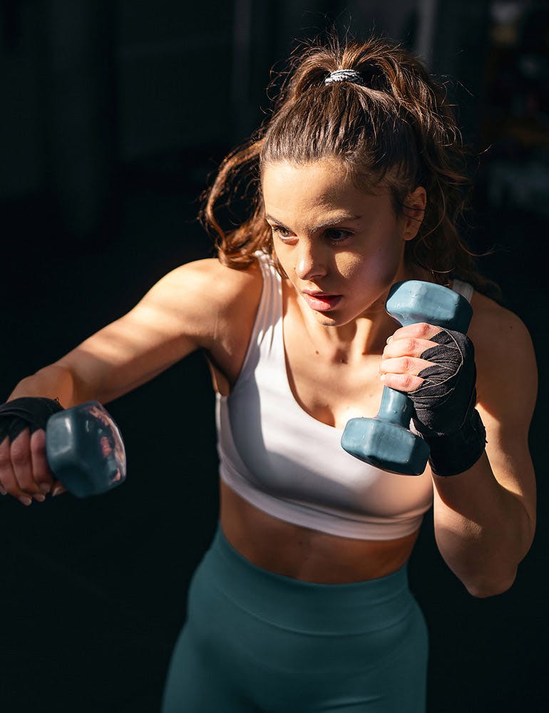 woman shadow boxing with dumbbells